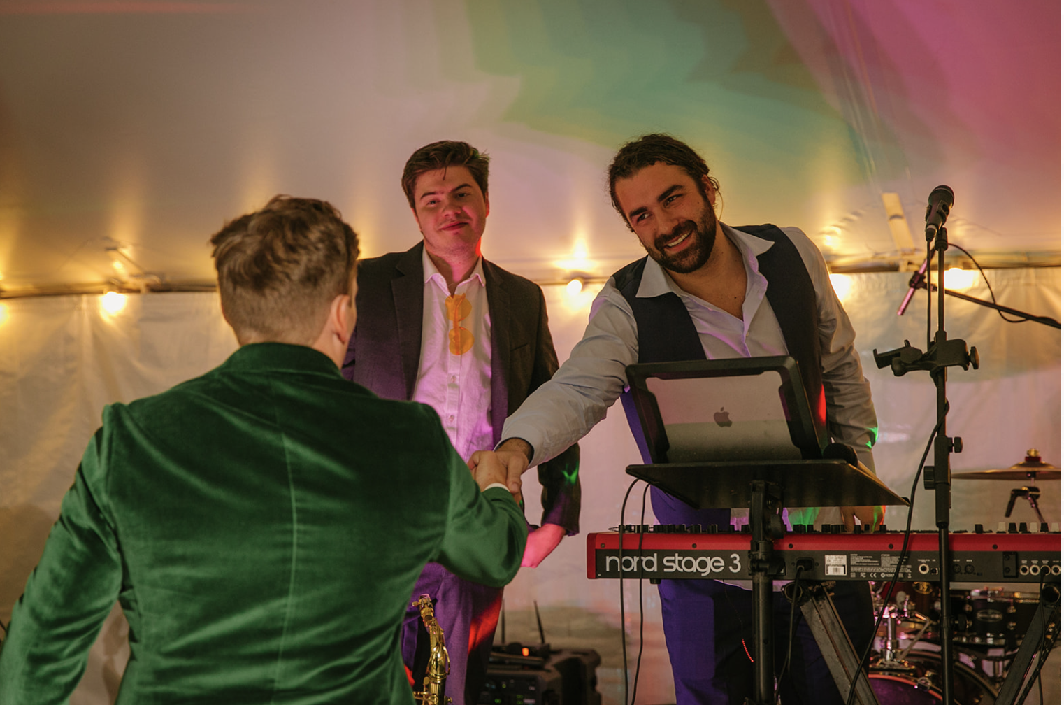 Keys and Company Events keyboardist shaking hands with a guest in a green velvet jacket during a tented wedding reception