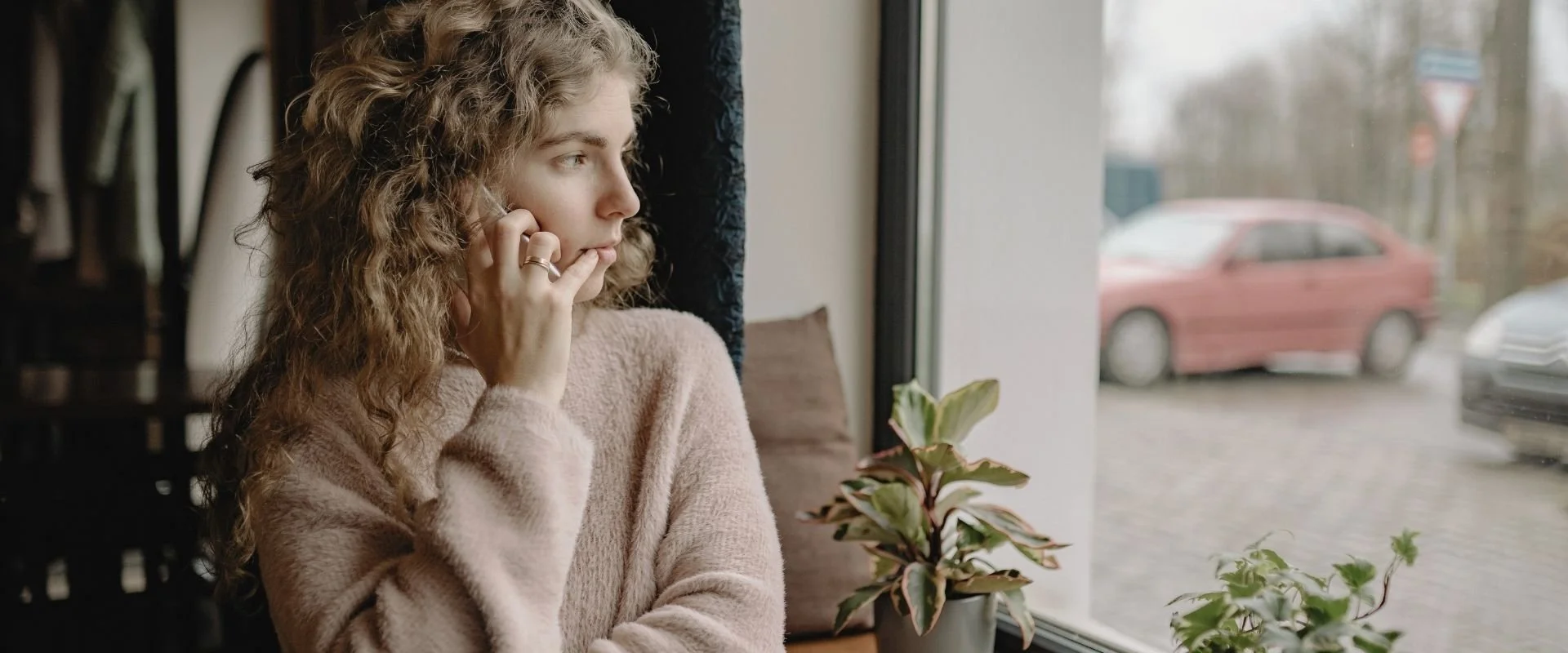 woman looking out a window jealous after child loss.