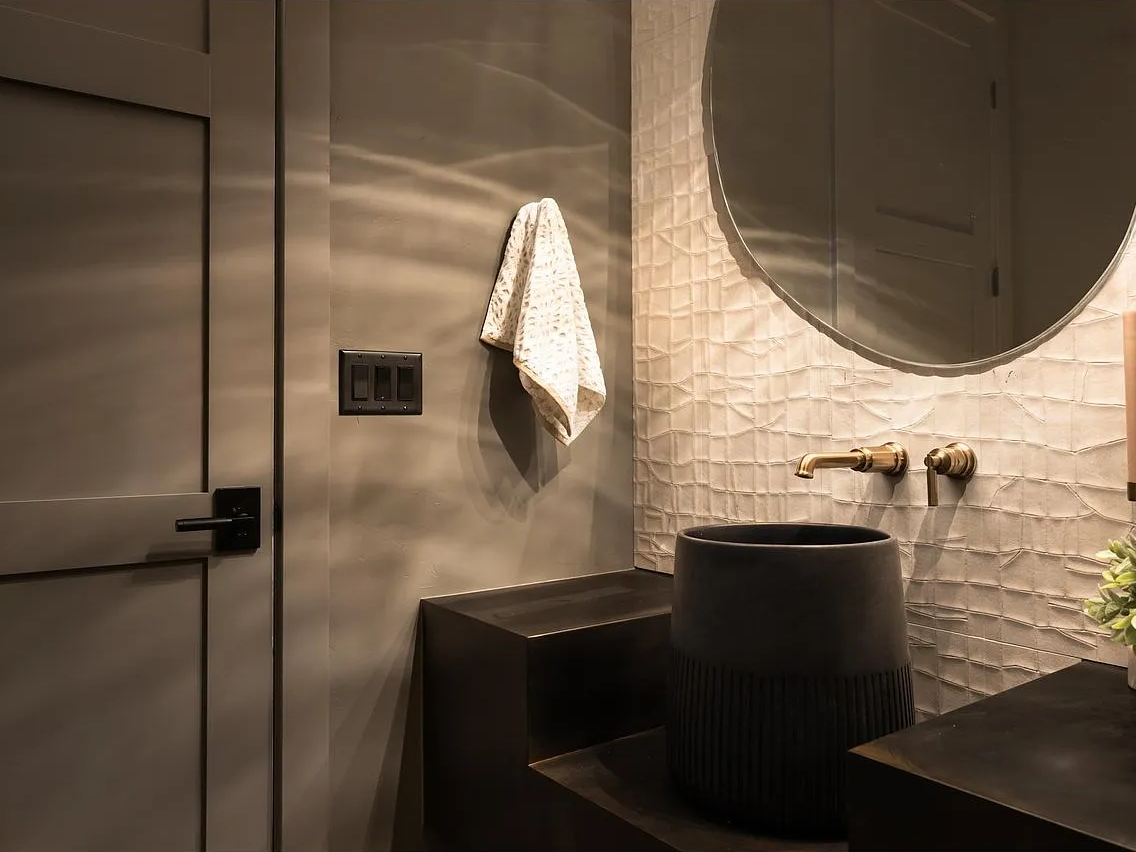 Venetian plaster catching light ripples beside the brass wall mount.