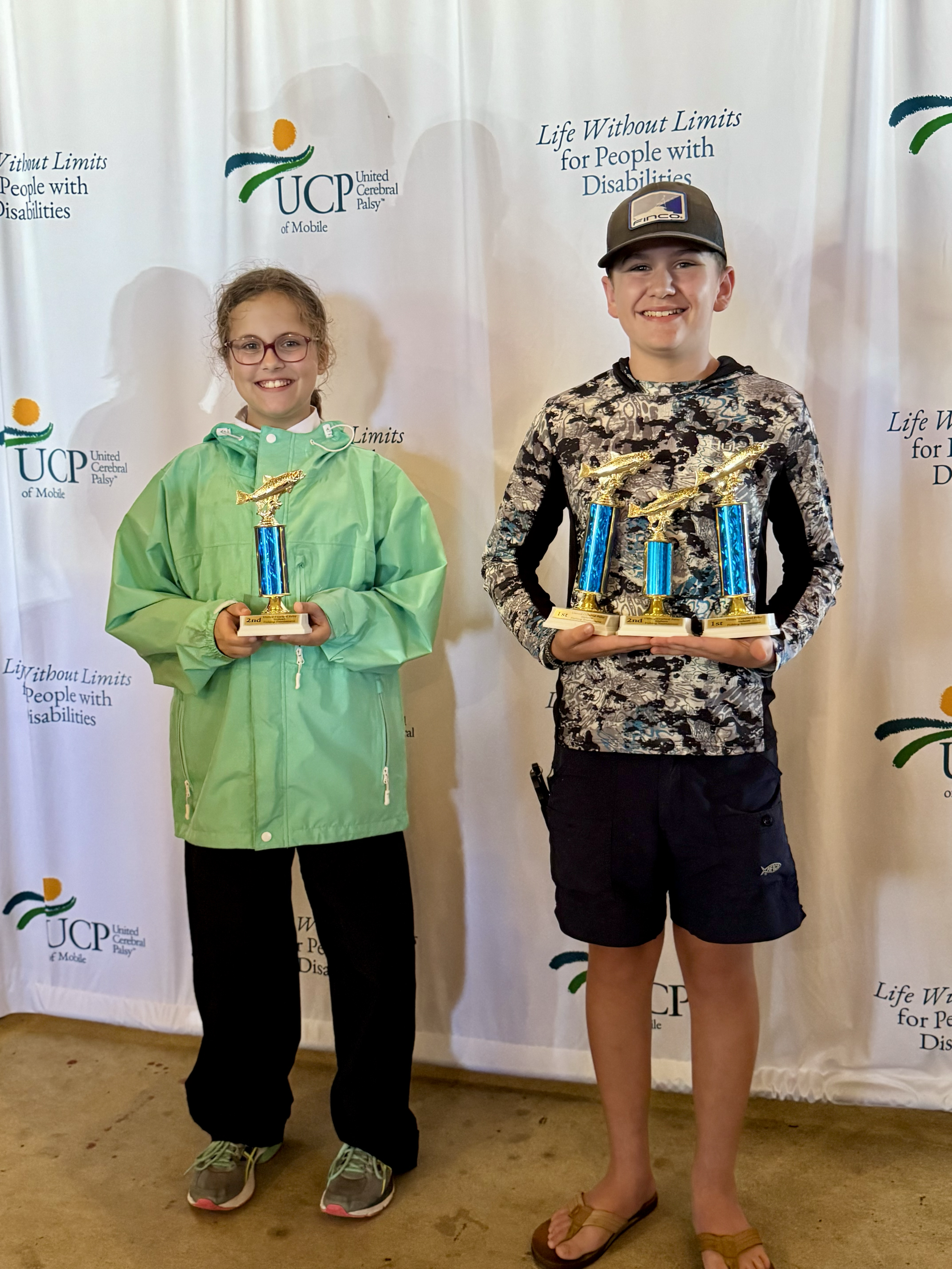 boy and girl holding fishing trophies