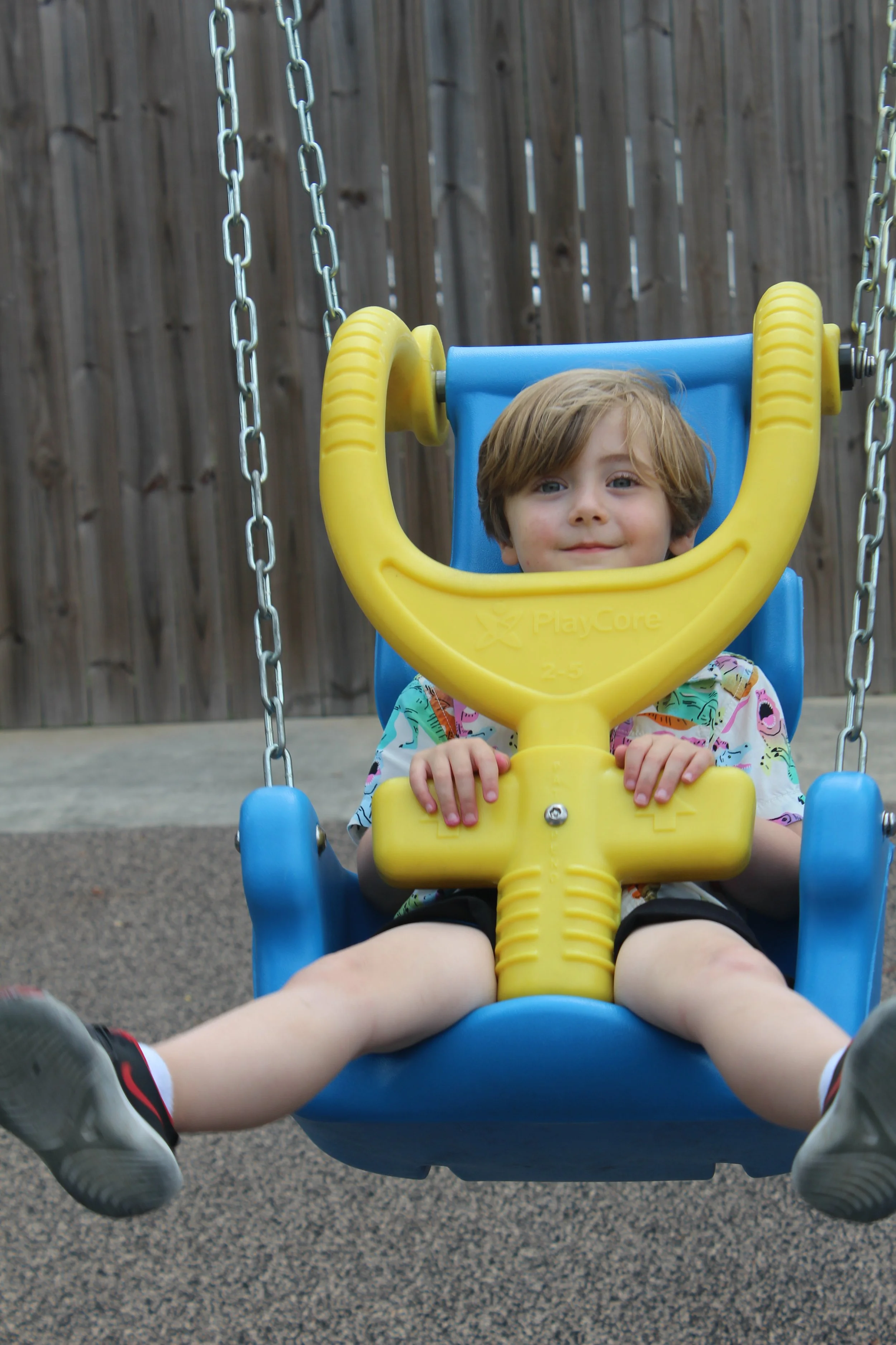 a male preschool student swings on the playground