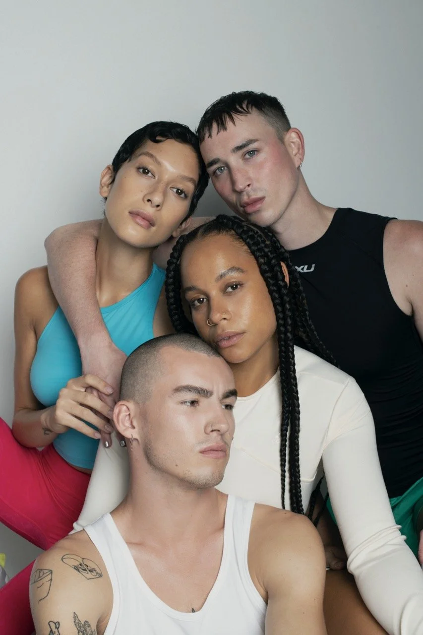 Group of five diverse young adults posing together against a plain background, displaying a confident and intimate vibe.