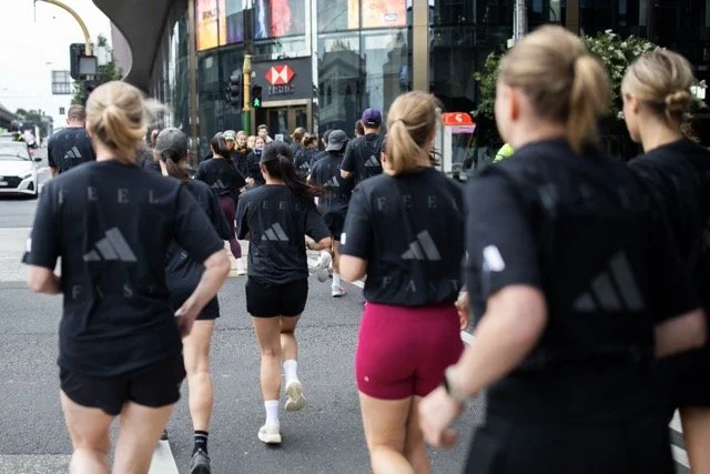Group of women running in an urban area, wearing athletic clothes with the FUEL logo.