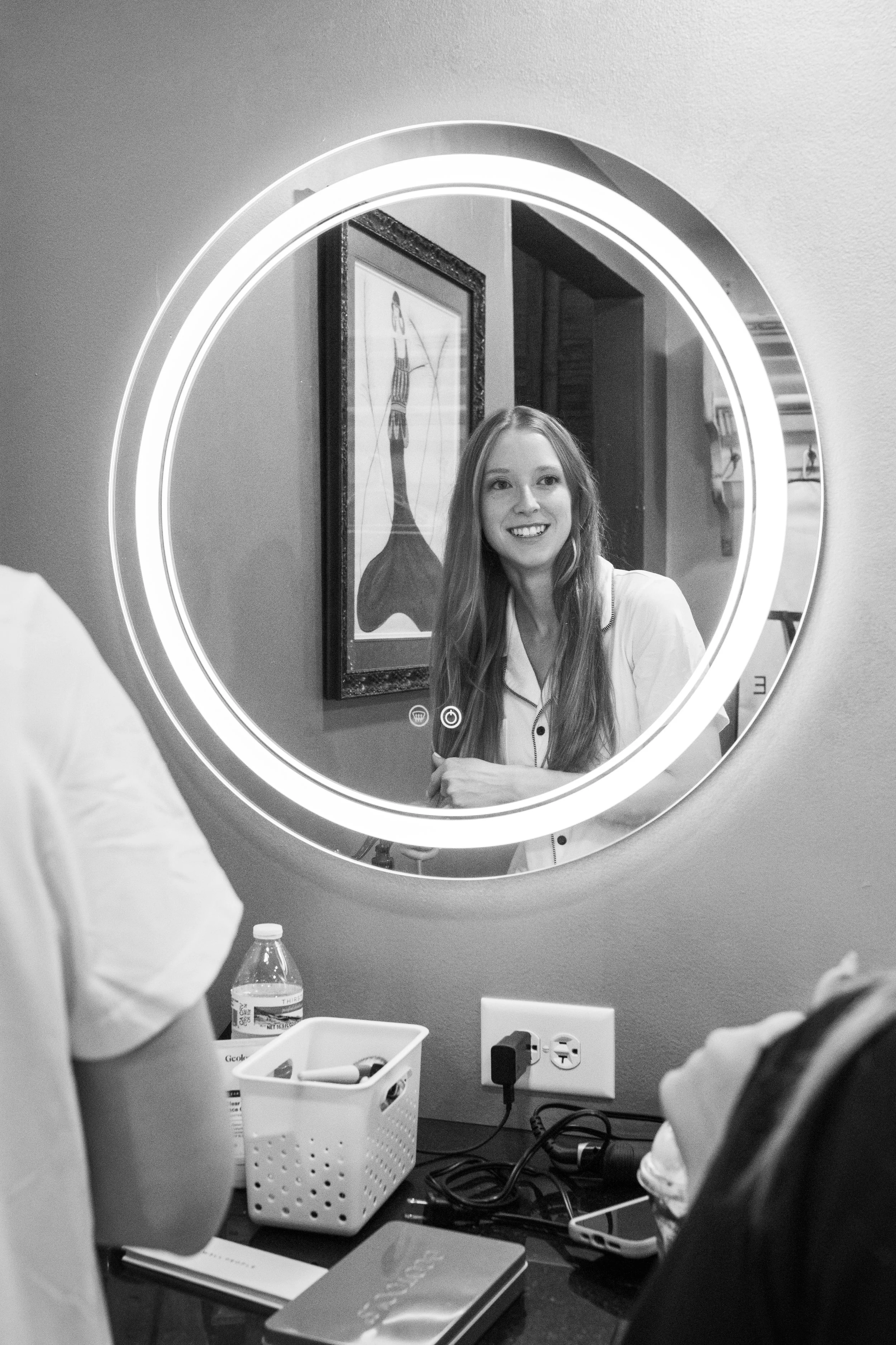 The bride chats while looking in a mirror.