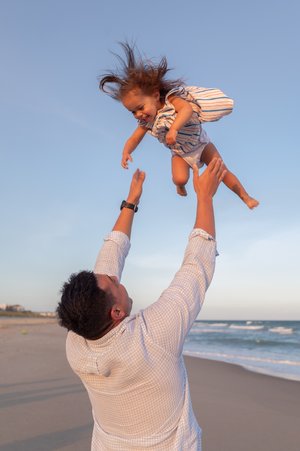 Family photography by Briana Woods: Dad plays with daughter at the beach at Emerald Isle, NC.