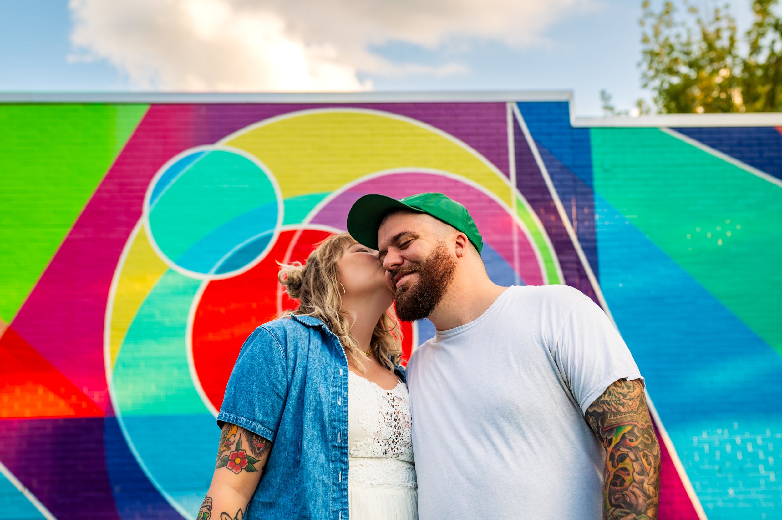 Couple photography by Briana Woods: Couple kissing in front of colorful mural in downtown Raleigh.