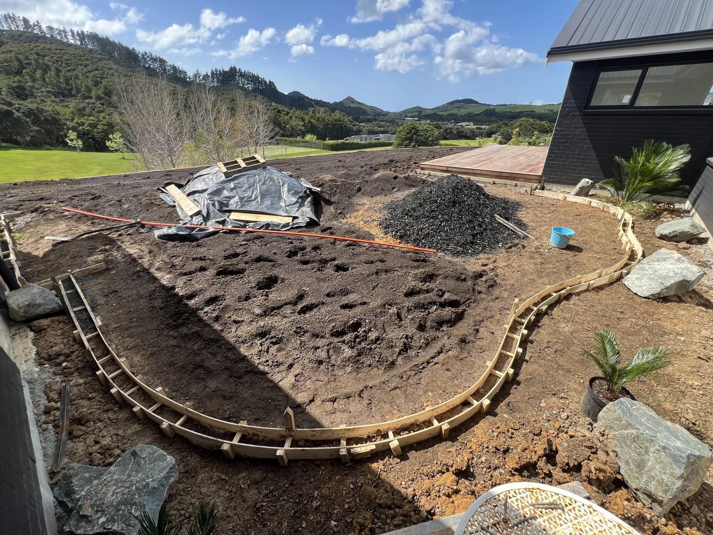 Site levelling and soil preparation for new build lawn with concrete mow strip in coastal northland town Mangawhai