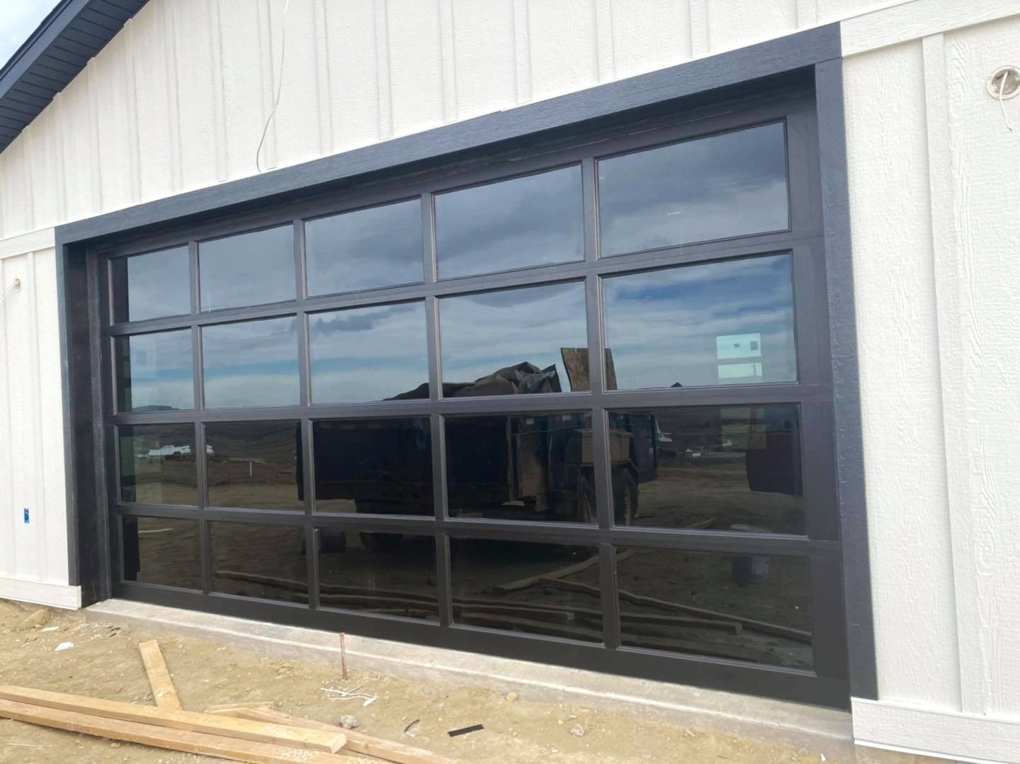 Large Glass commercial garage door installed on a white building by Vazquez Garage Doors and Gutters