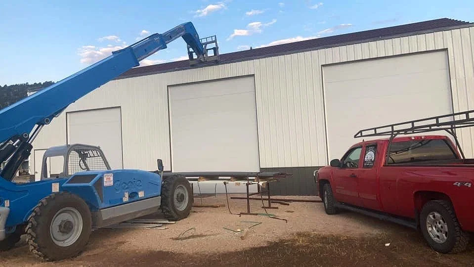 Three large commercial garage doors installed on a tan building by Vazquez Garage Doors and Gutters