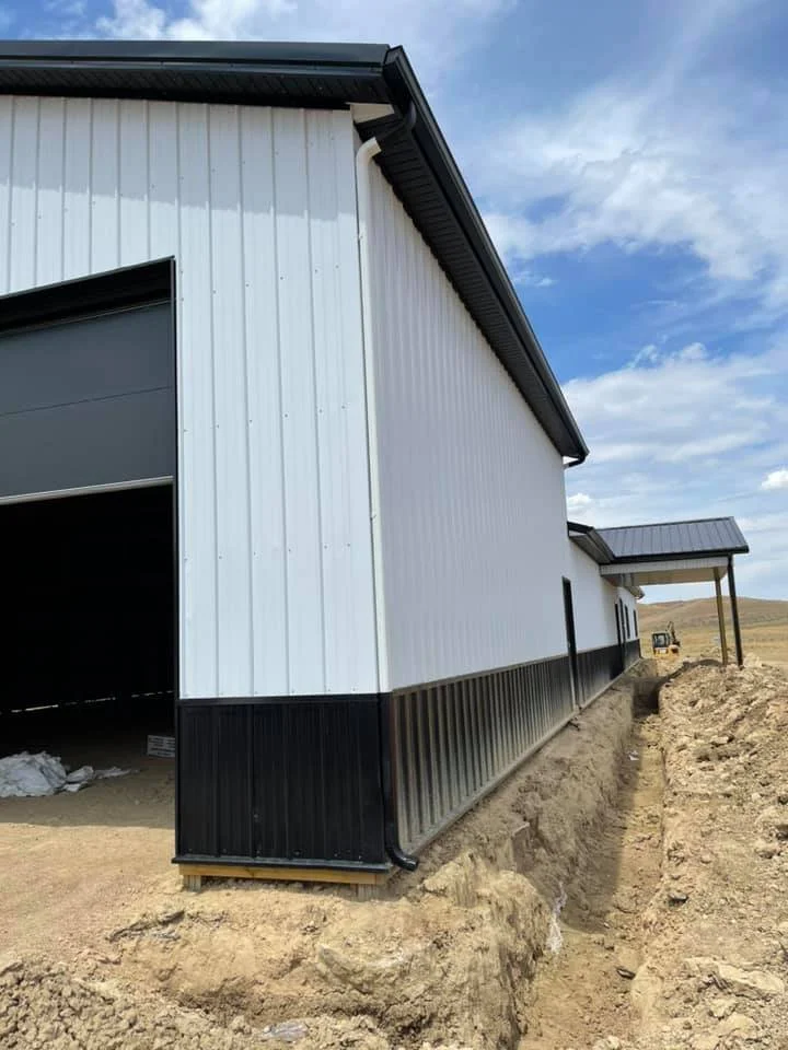 Large white and black building with gutters installed by Vazquez Garage Doors and Gutters