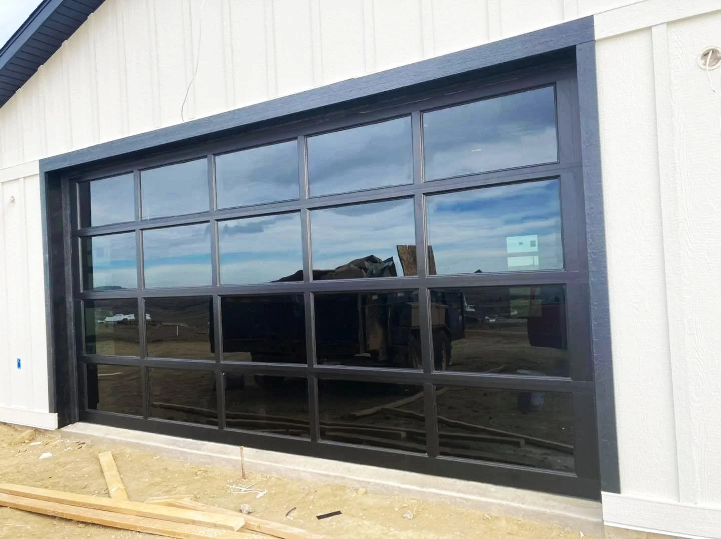Large white building with a glass commercial garage door installed by Vazquez Garage Doors and Gutters