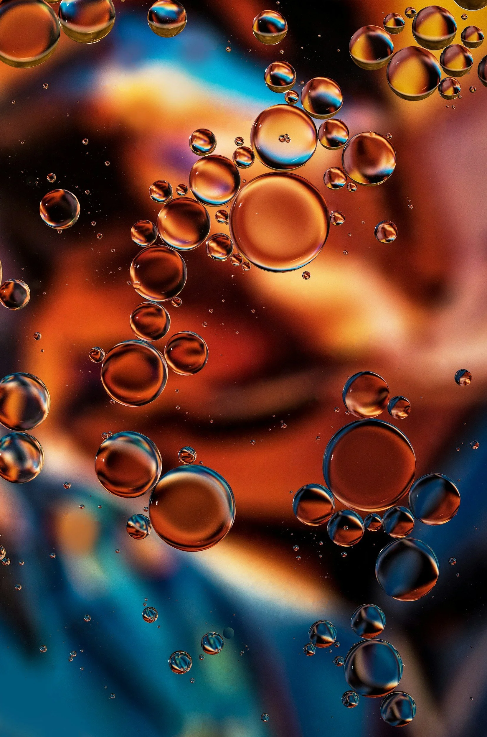Close-up of oil droplets suspended in water, with colorful blurred background.