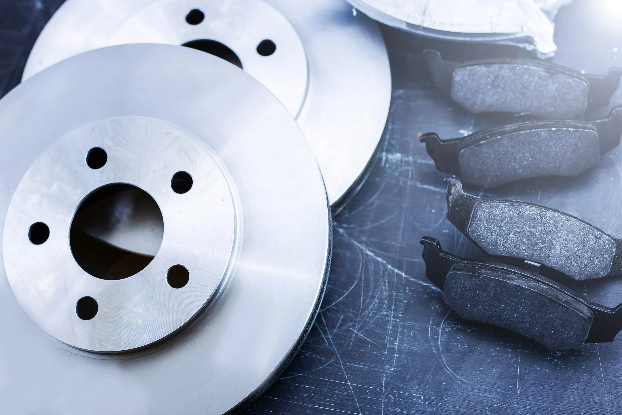 Ceramic brake pads and geocoated rotors laid out on a work bench, ready for the RDS Automotive Service team to install on a vehicle.