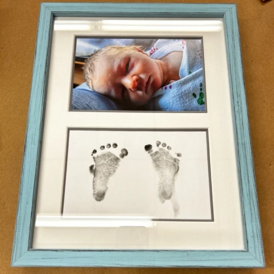 Framed photo of new born baby with foot prints in light blue frame