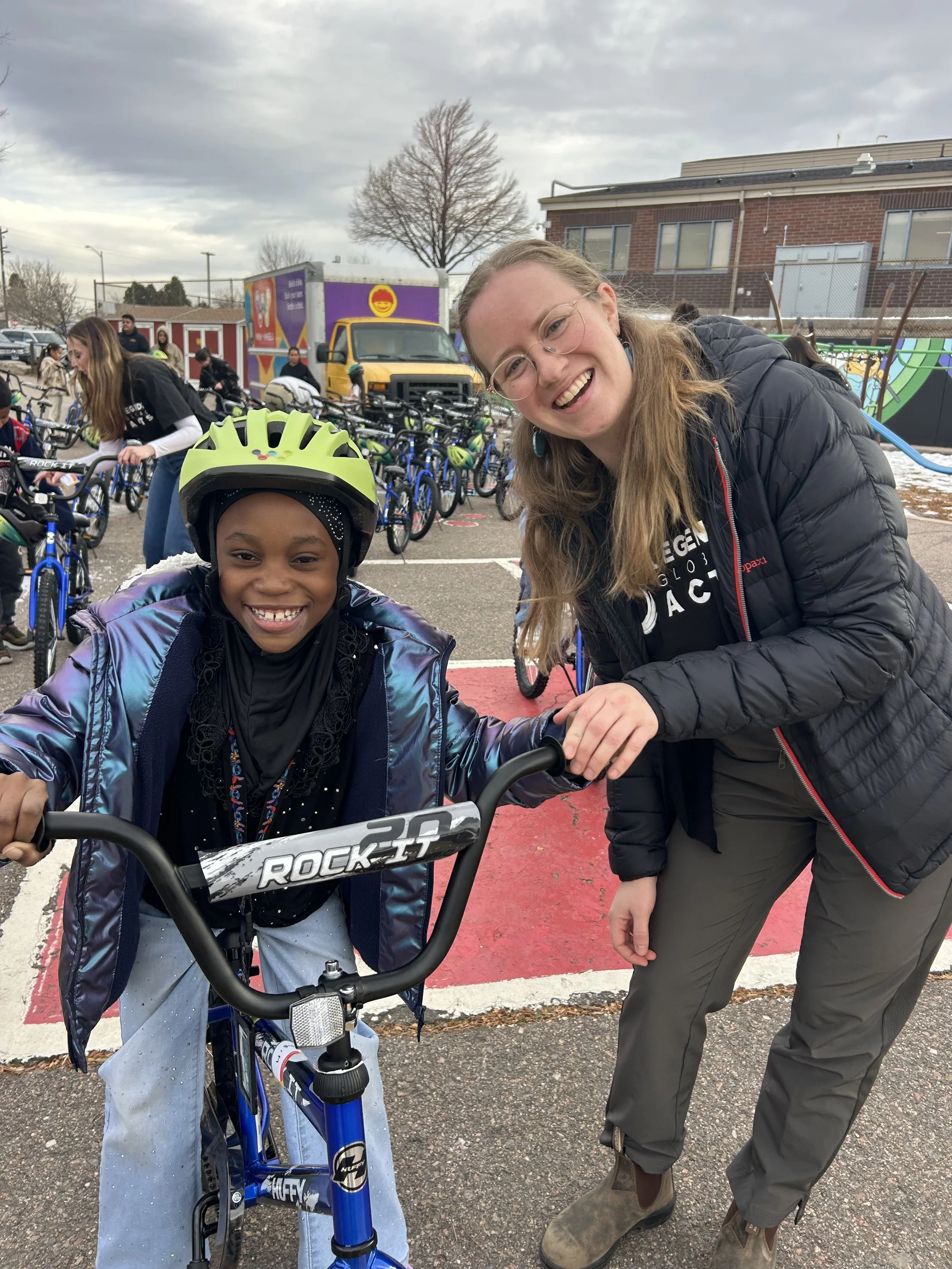 Employee and student with bike and helmet standing together at Wish for Wheels corporate team building event.