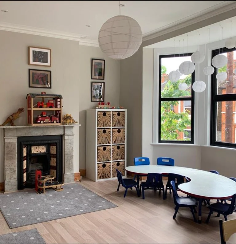 Bright nursery classroom with child-sized tables, storage units and large windows