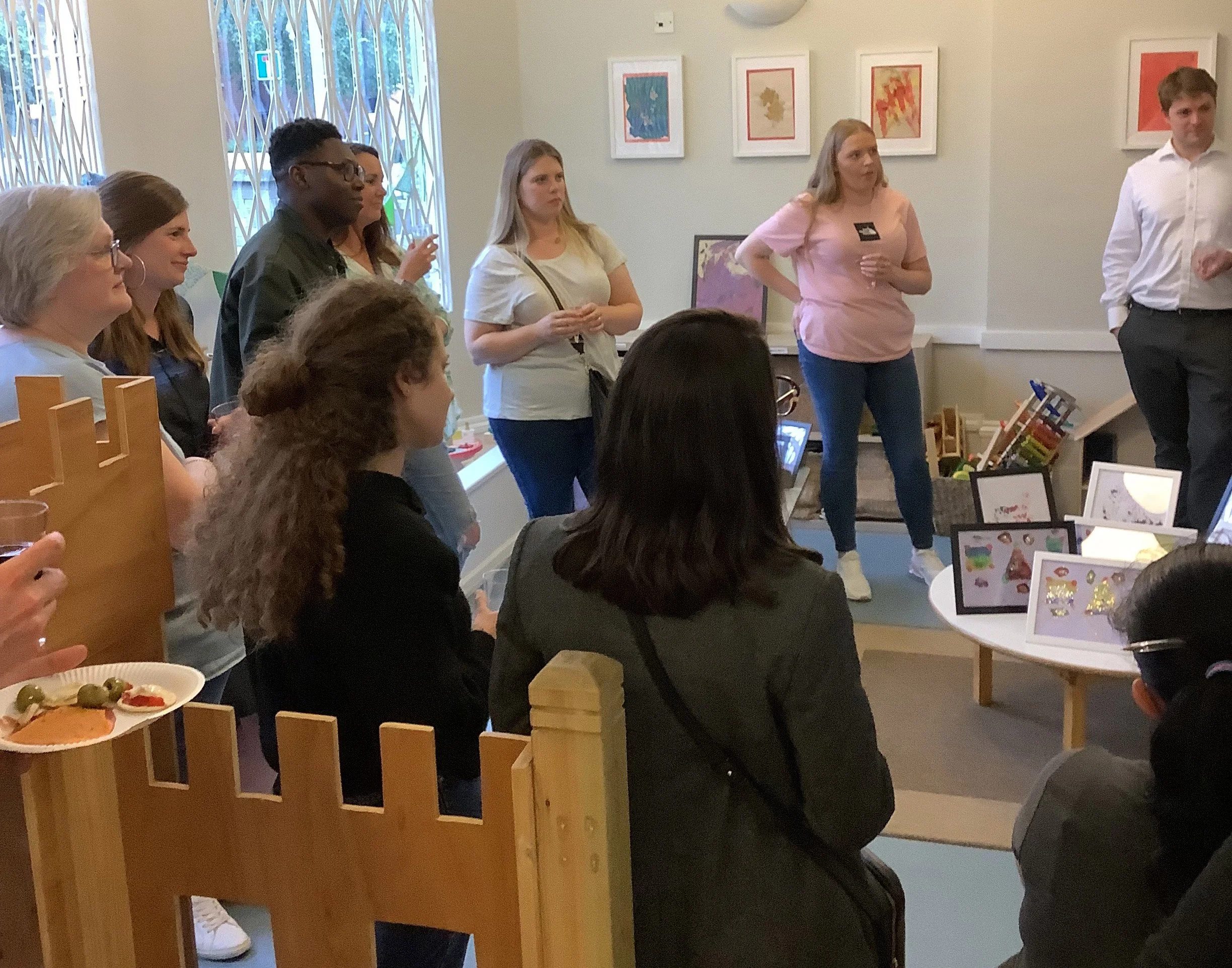 Parents and staff gathering for a social coffee morning inside a bright nursery classroom.