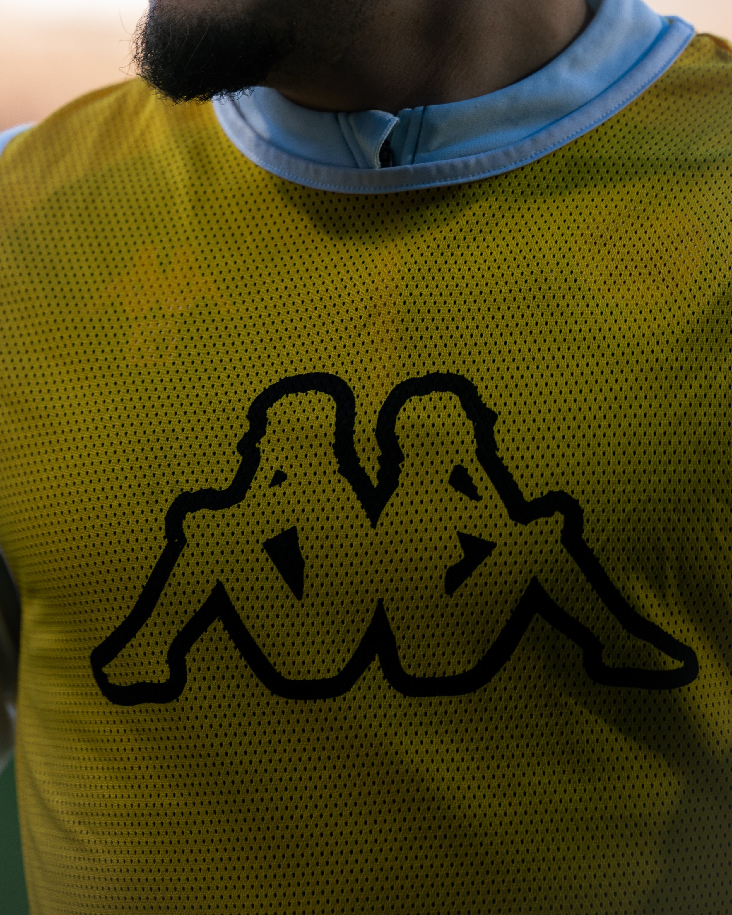 Un détail d'un joueur de football portant un chasuble. Il fait partie de l'équipe du Red Star et porte le logo de l'équipementier Kappa.