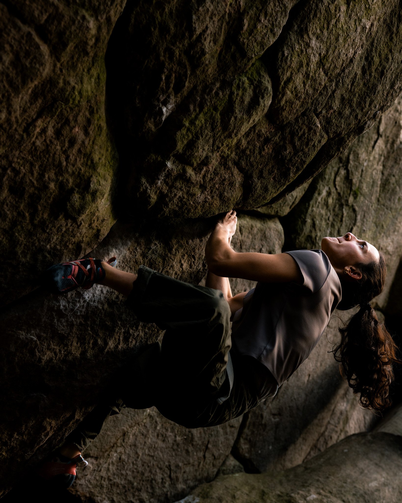 Une photographie de la grimpeuse française Zelia Avezou dans la forêt de Fontainebleau. Elle travaille ici un bloc de cotation élevée. Elle travaille ici un bloc de cotation élevée, la veille du contest Team Boulder Arena organisé par Climbing Distri