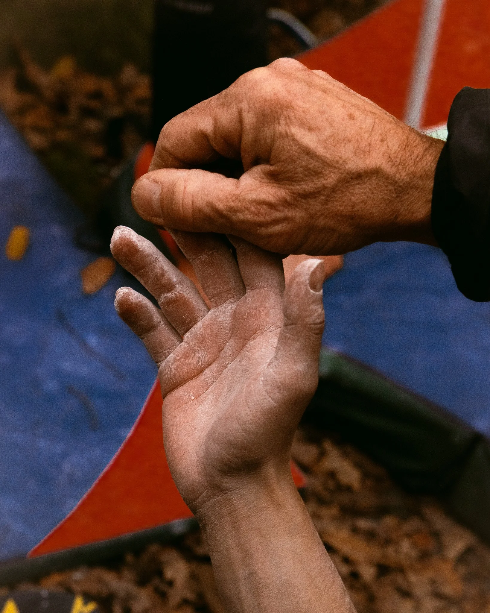 Une main d'adulte aide une main d'enfant à faire un nœud avec une corde blanche.
