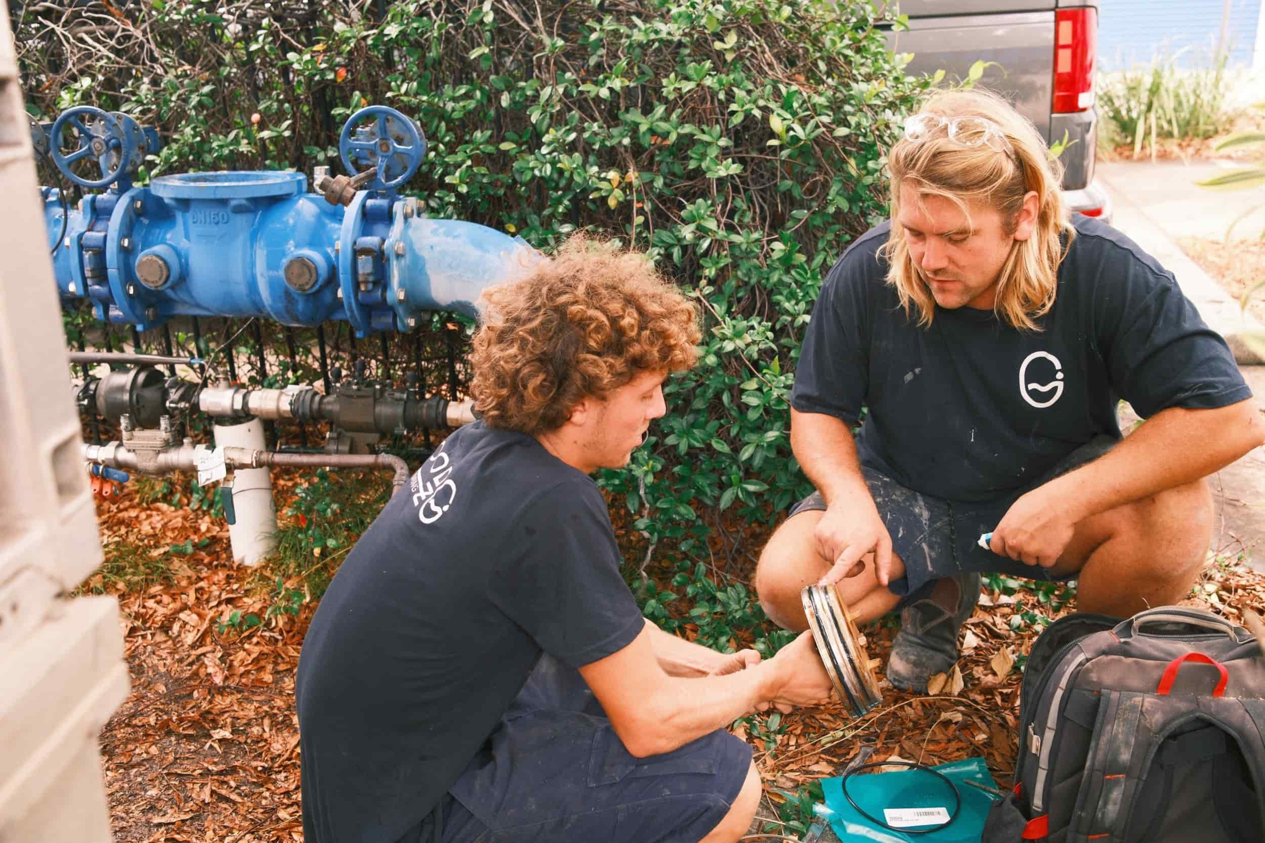 a tradesman and apprentice servicing a backflow prevention device