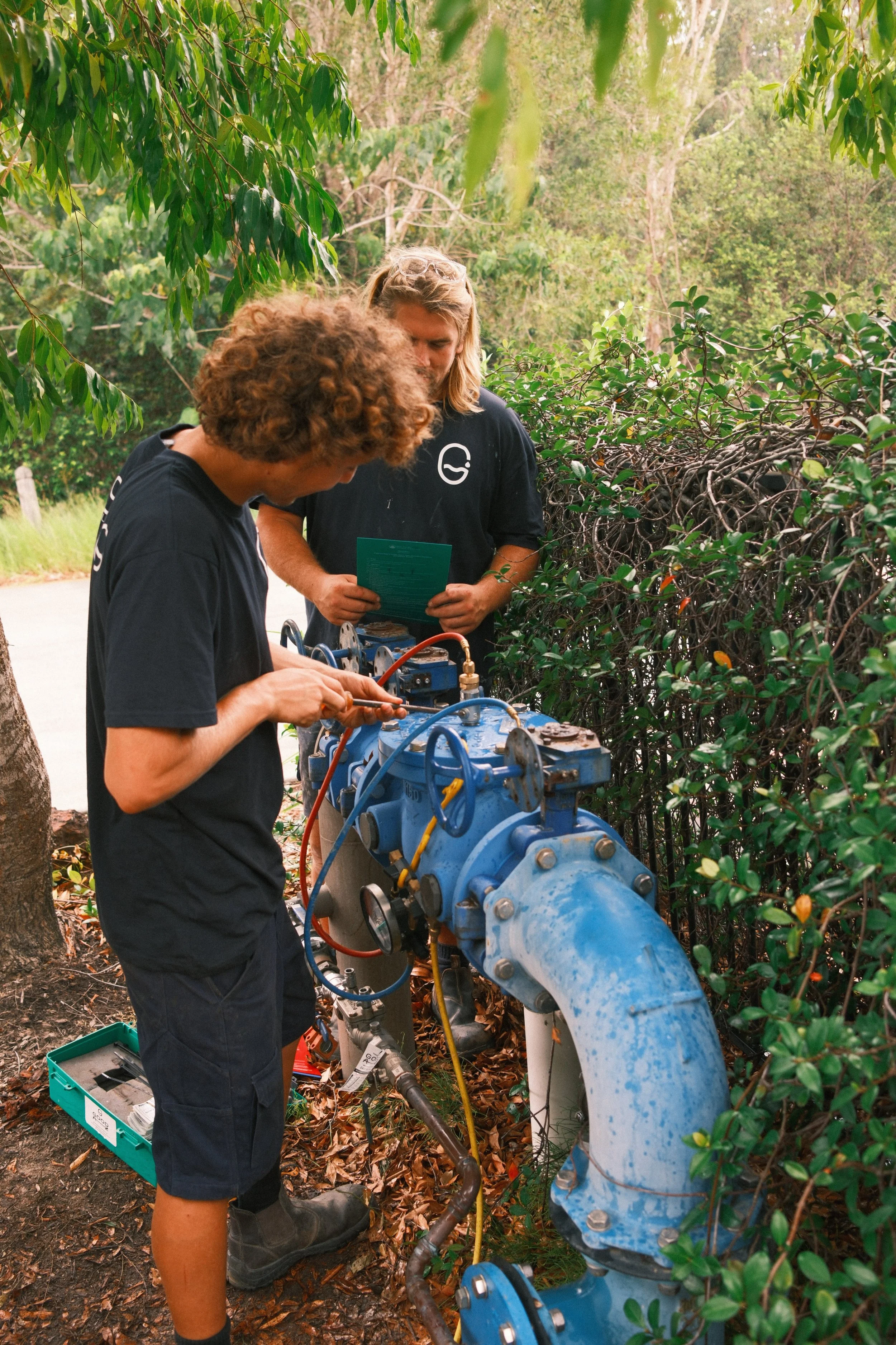 Tradesman and apprentice testing a backflow prevention valve at a commercial property
