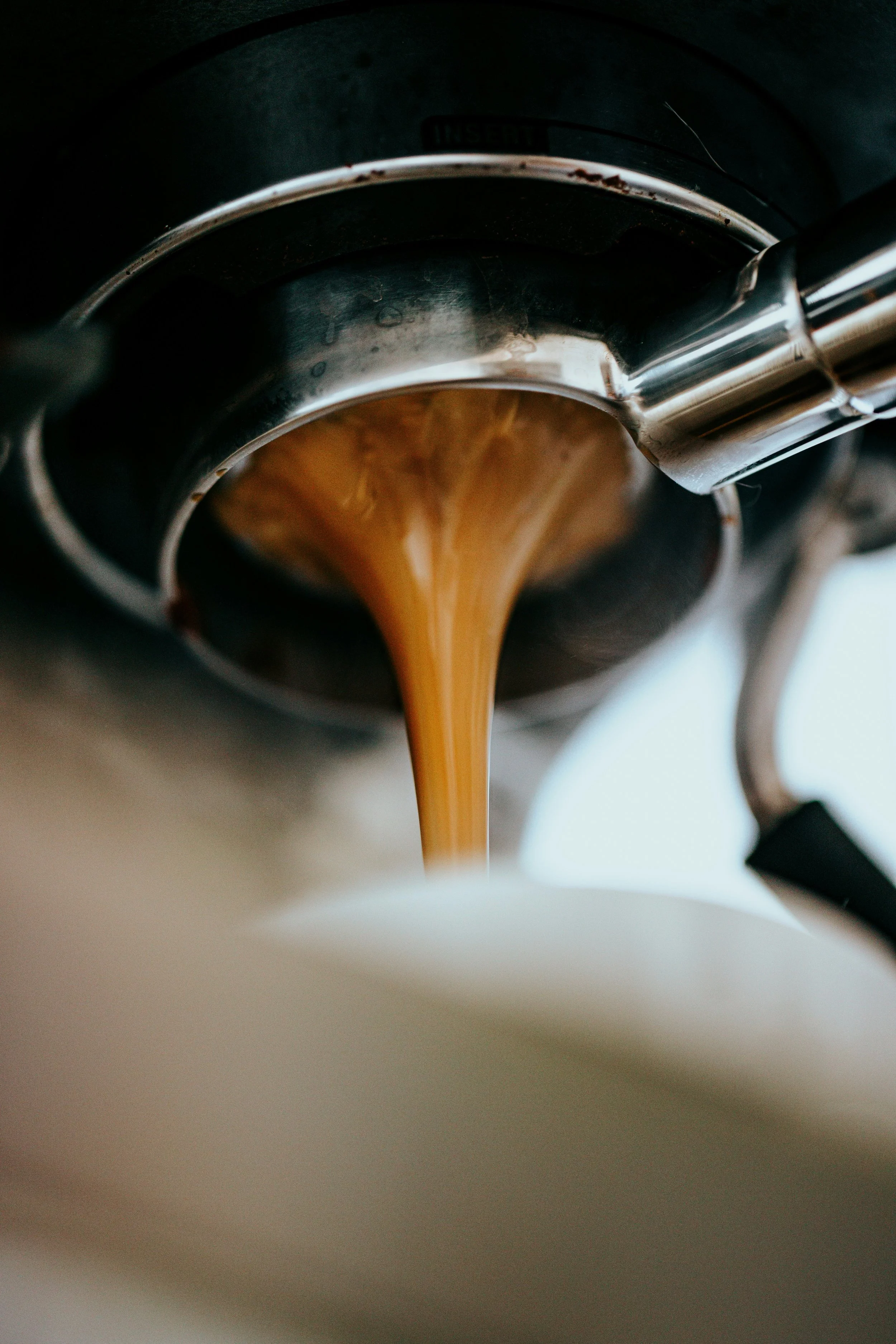 Nahaufnahme von frischem, fließendem Kaffee aus einer Espressomaschine.