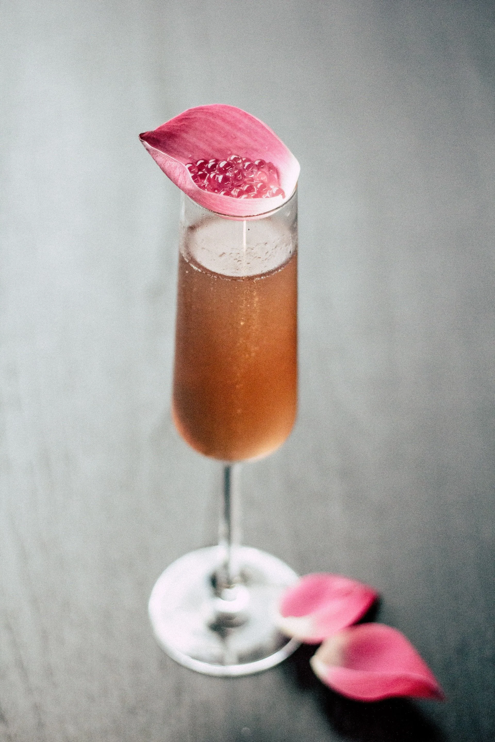 Ein Sektglas mit rosafarbenem Blumenblatt und Beeren als Dekoration