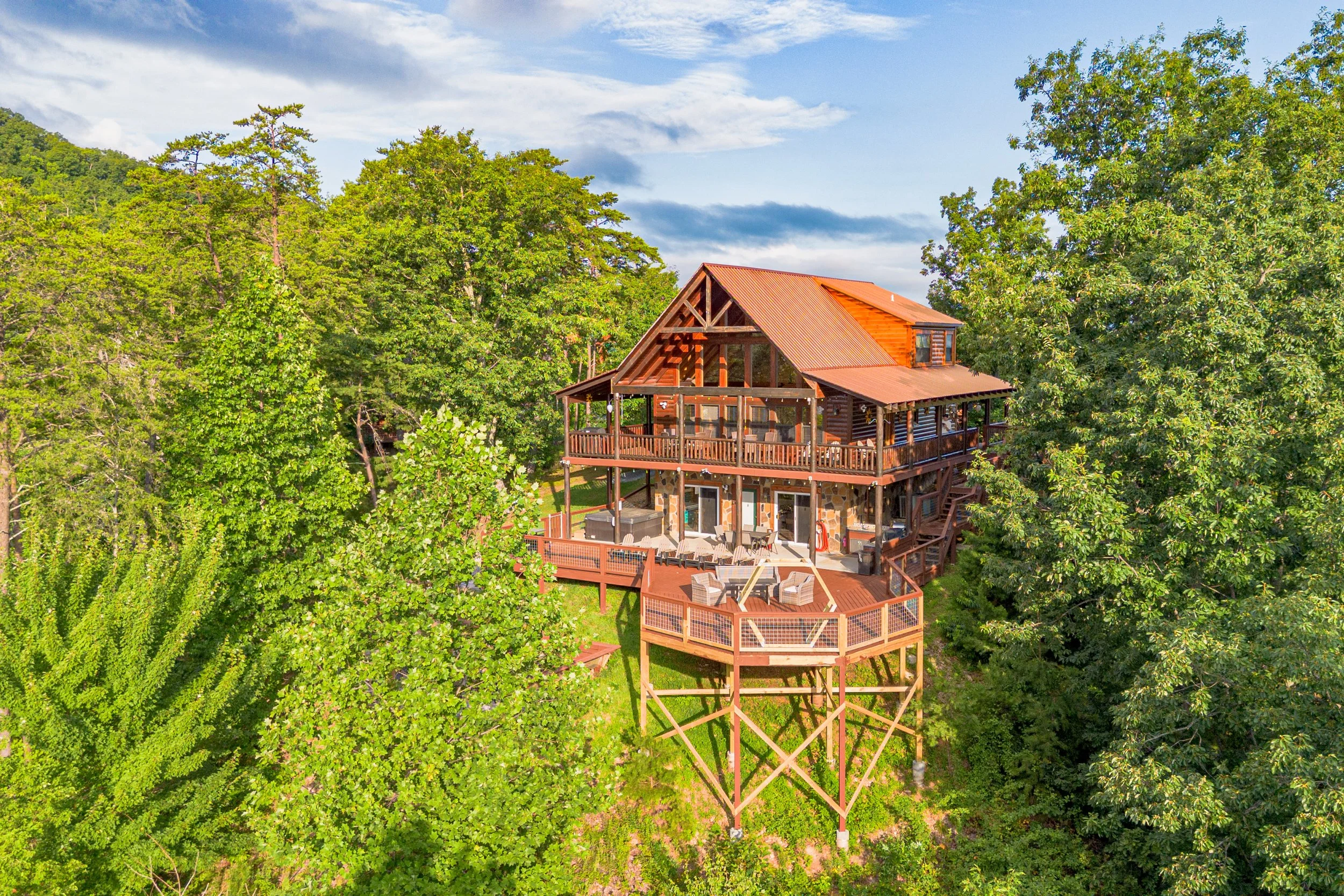 A multi-story wooden house on stilts surrounded by lush green trees in a forest area.