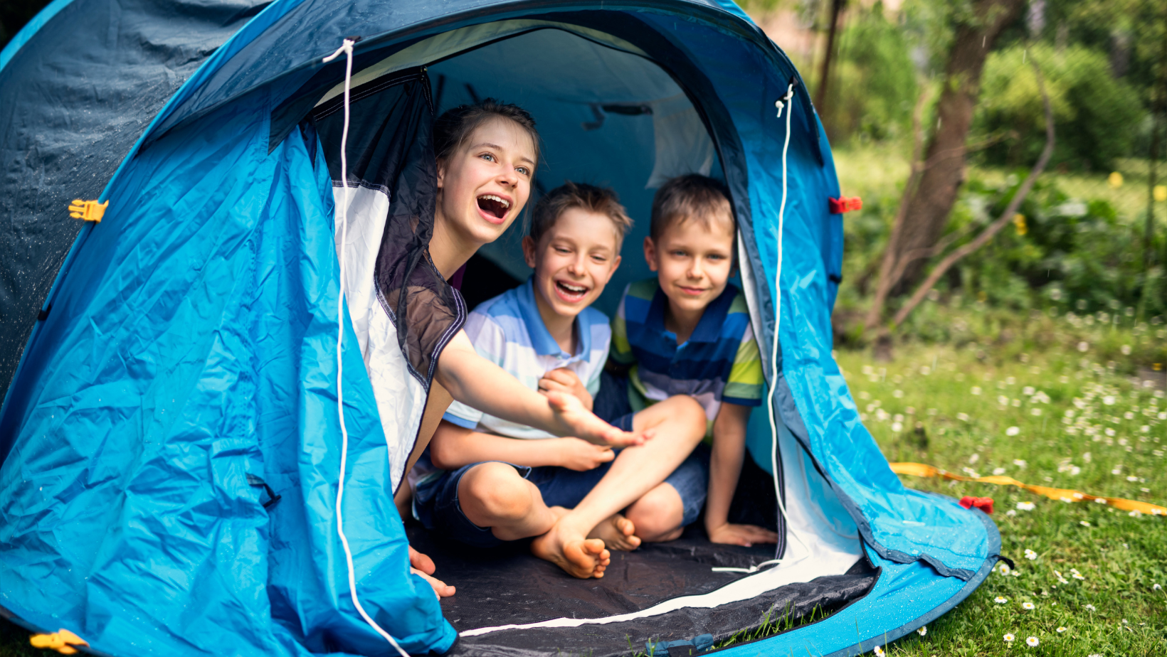 3 enfants sont dans une tente de camping, à l'abris de la pluie