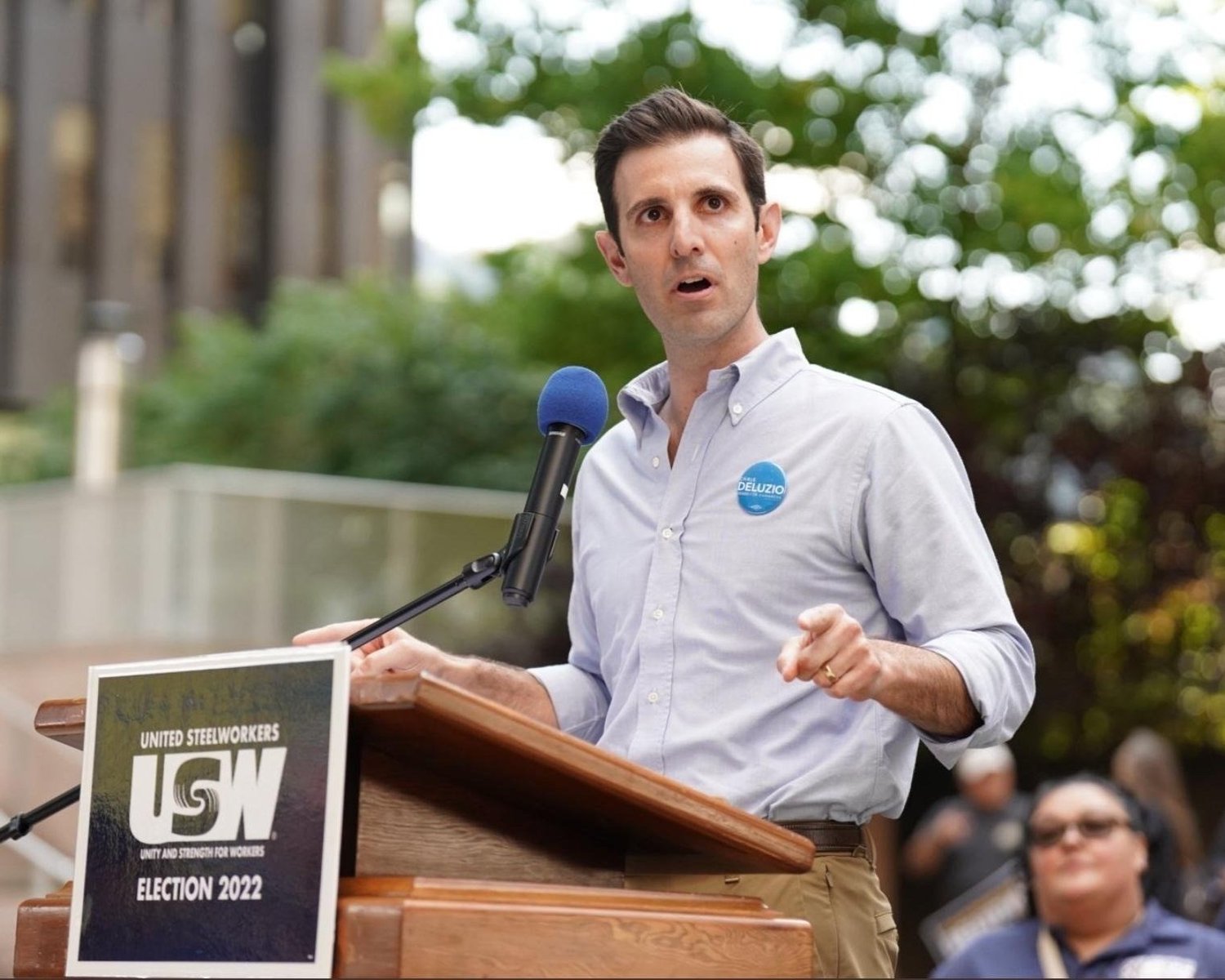 Chris DeLuzio speaks behind a brown podium with a sign that reads "United Steelworkers USW Election 2022." 