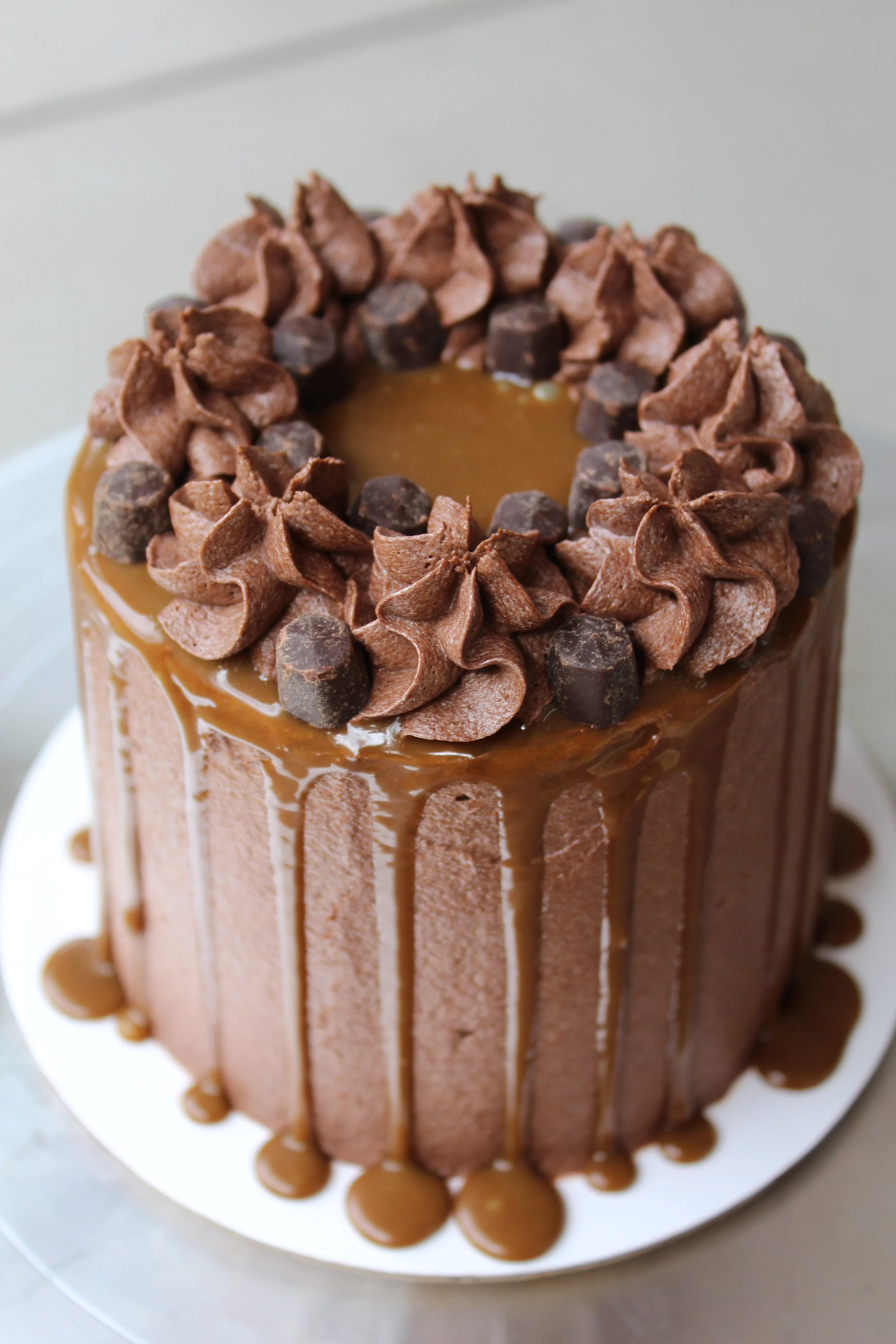 Chocolate cake with caramel glaze, topped with chocolate frosting rosettes and chocolate chips.