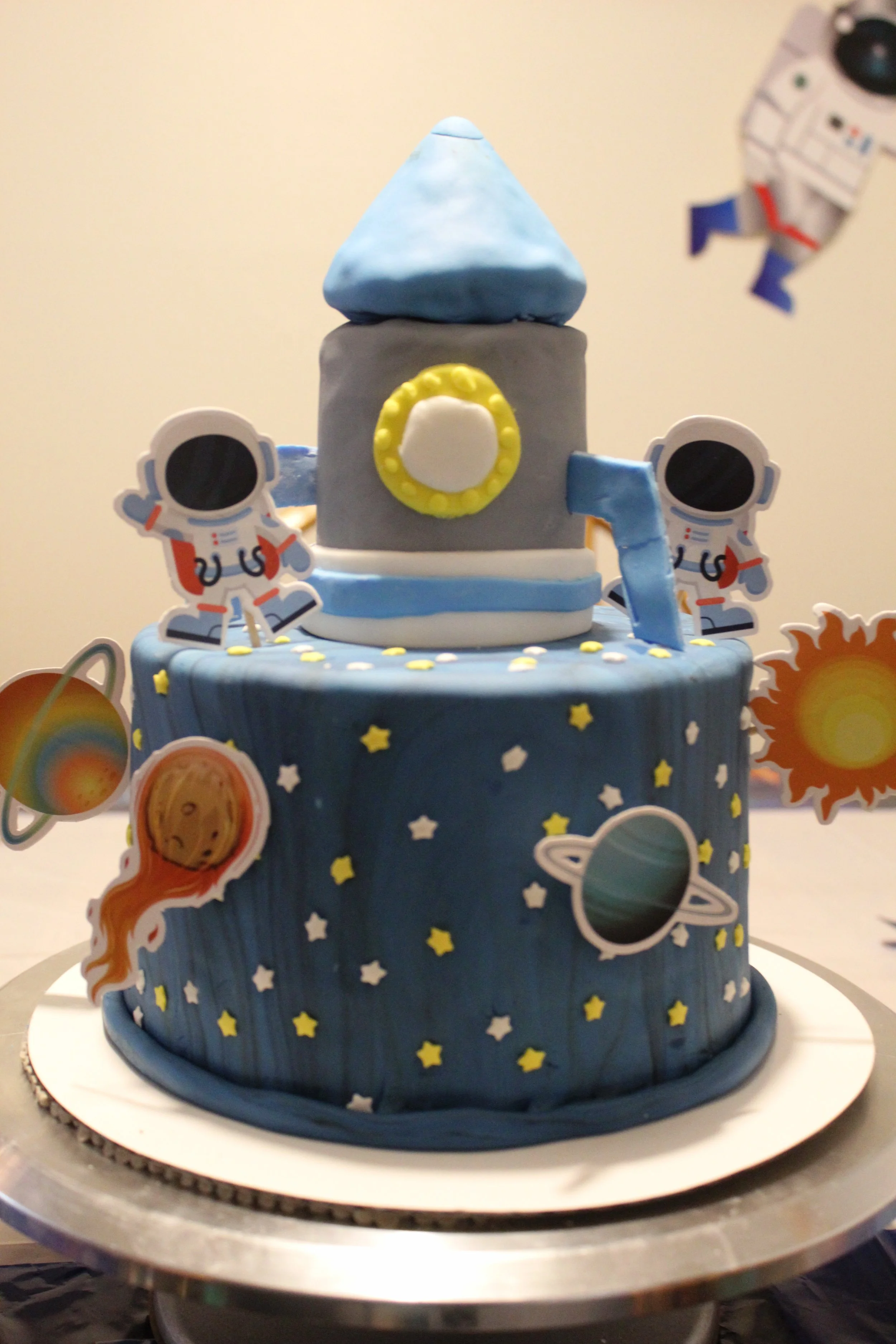 Space-themed birthday cake with astronaut, planets, and rocket decorations.