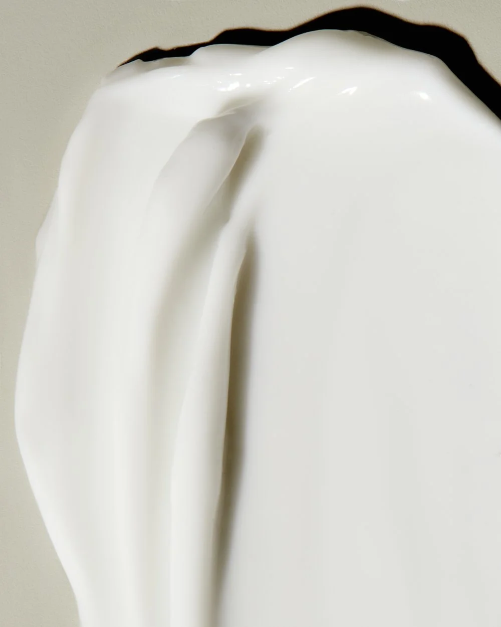 Close-up texture shot of glossy cream curving into a smooth fold, by Adrianna Favero.