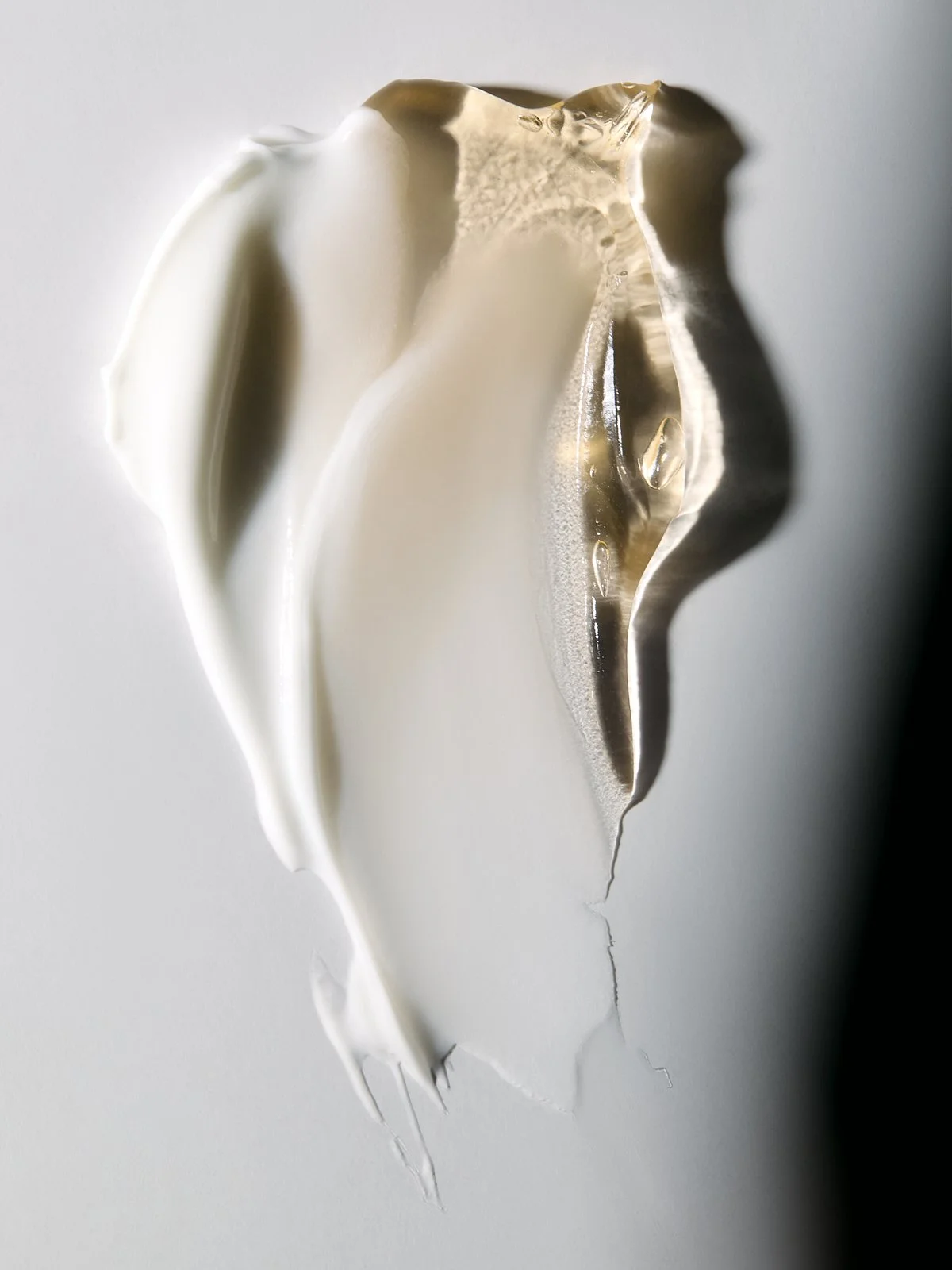 Close-up texture shot of a cream lotion smear on a grey background, by Adrianna Favero.