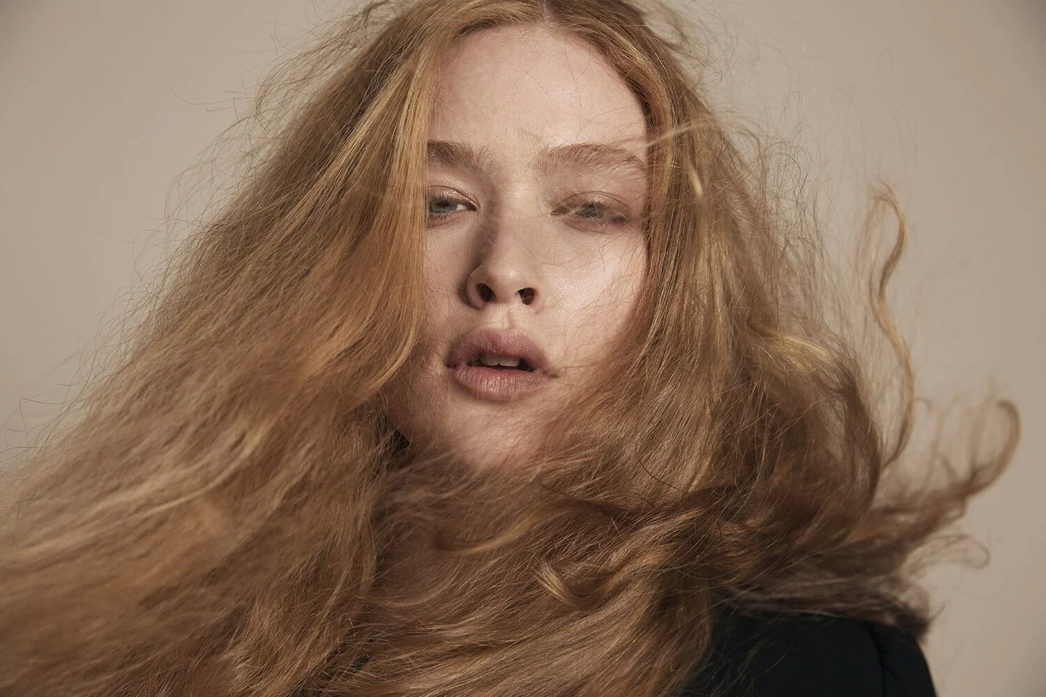 Woman with long flowing hair, neutral expression, wind-blown effect.