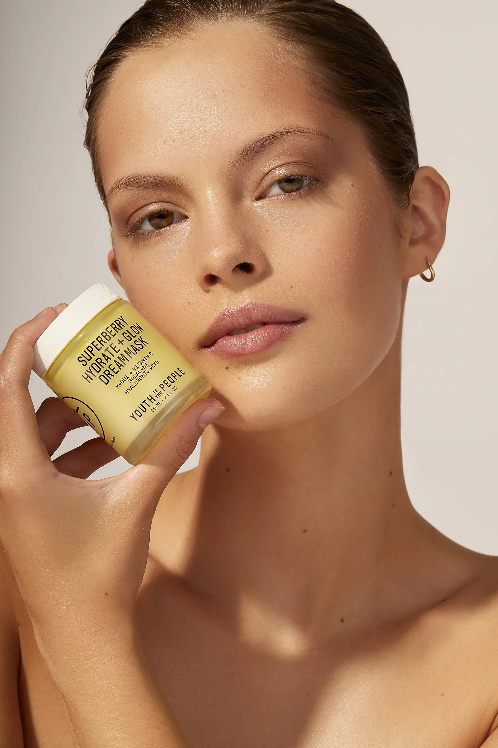 Person holding Youth to the People Superberry Hydrate + Glow Dream Mask jar close to their face.