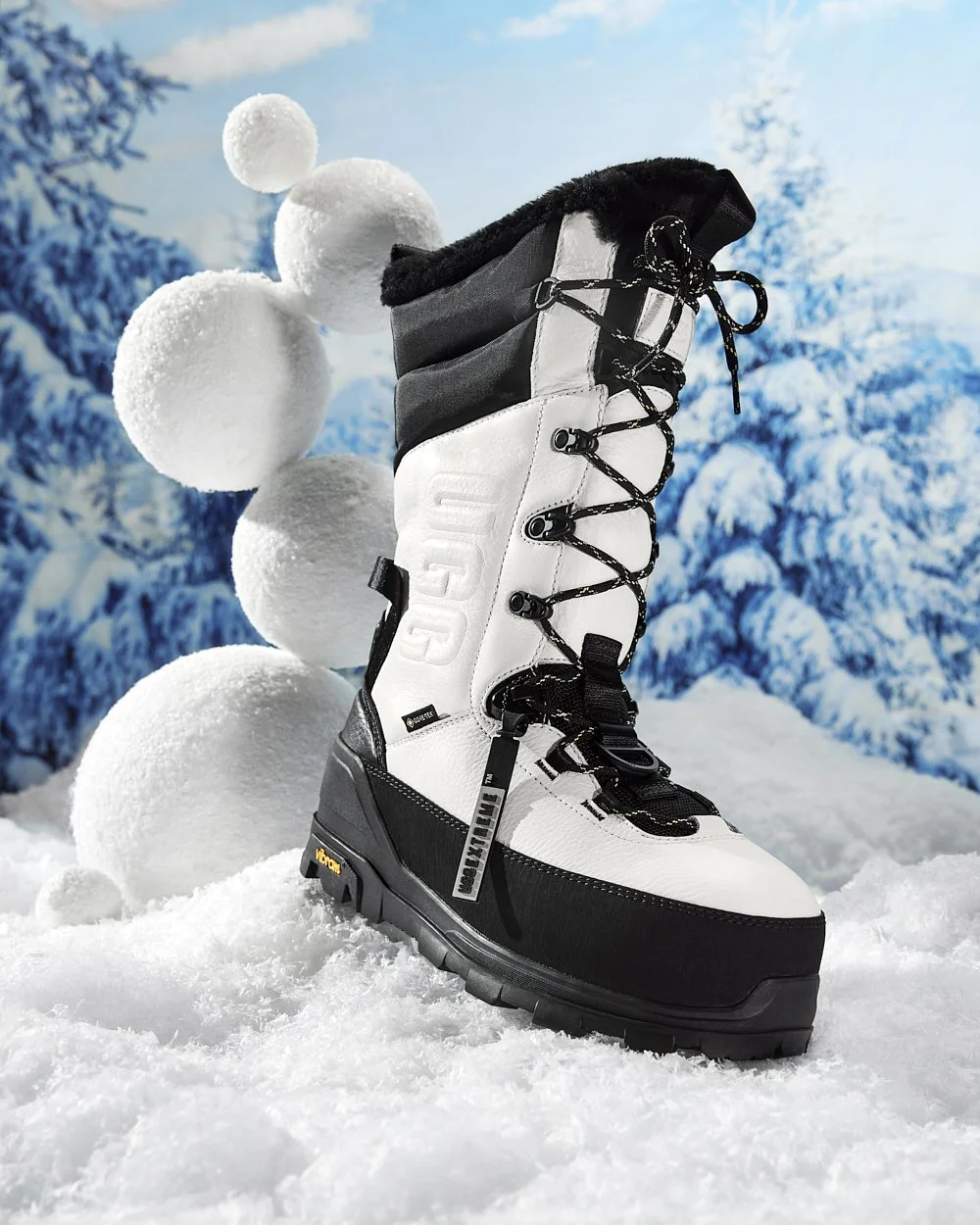 Winter boot with black and white design on snow, with snowballs in the background.