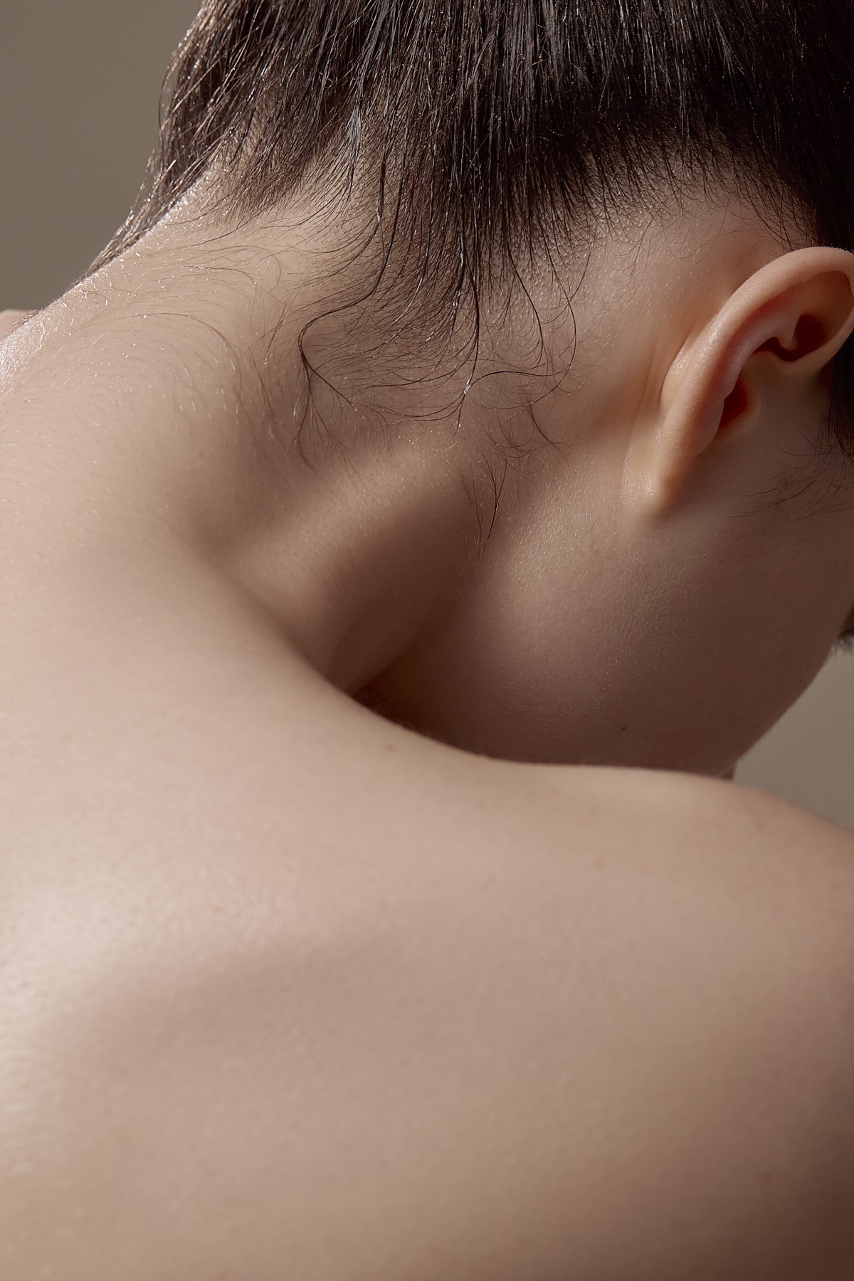 Beauty close-up of a model's nape and shoulder with hair swept back, highlighting smooth skin texture for a skincare and beauty brand campaign by Adrianna Favero, NYC beauty photographer and director.