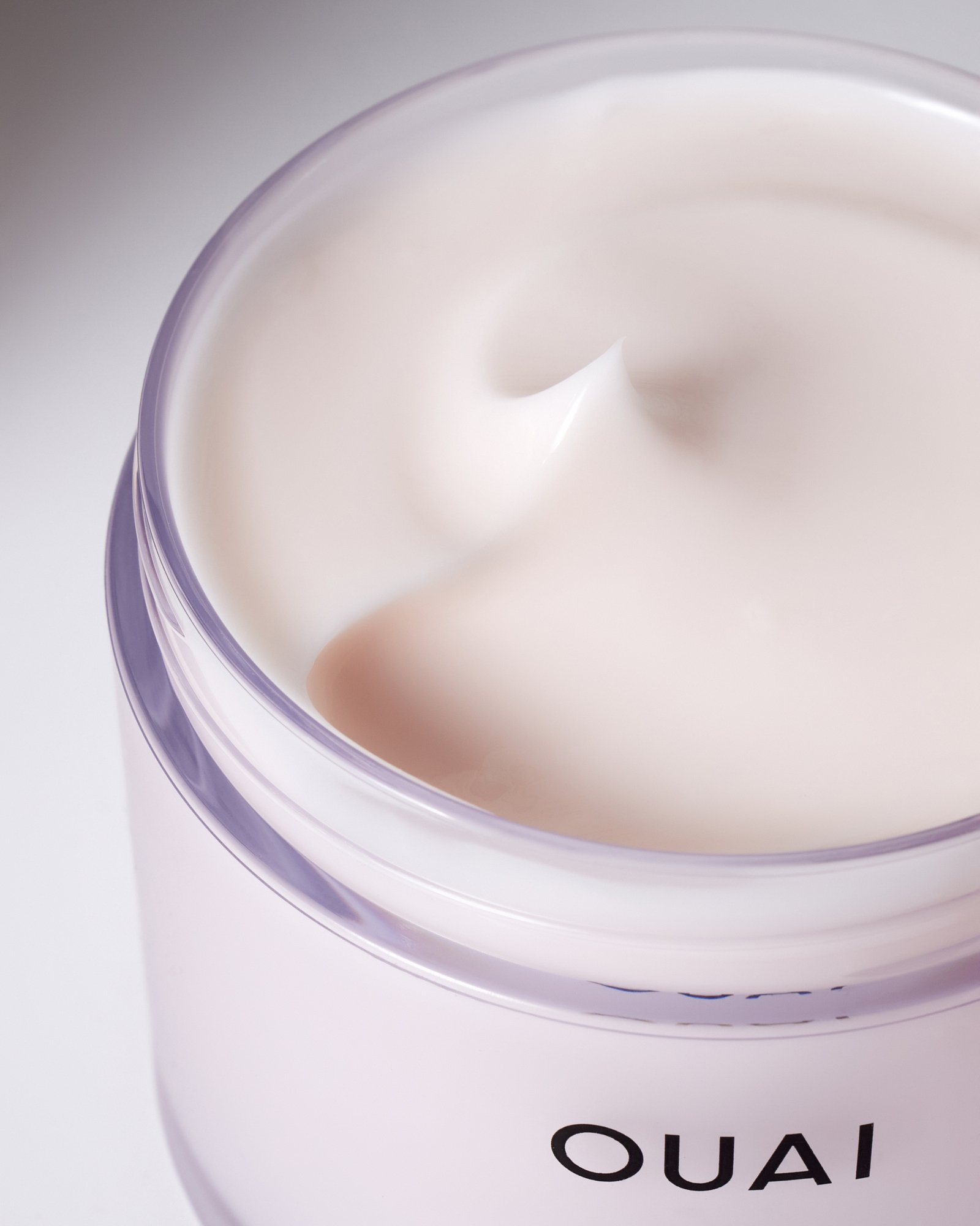 Cream in an open jar labeled "OUAI"