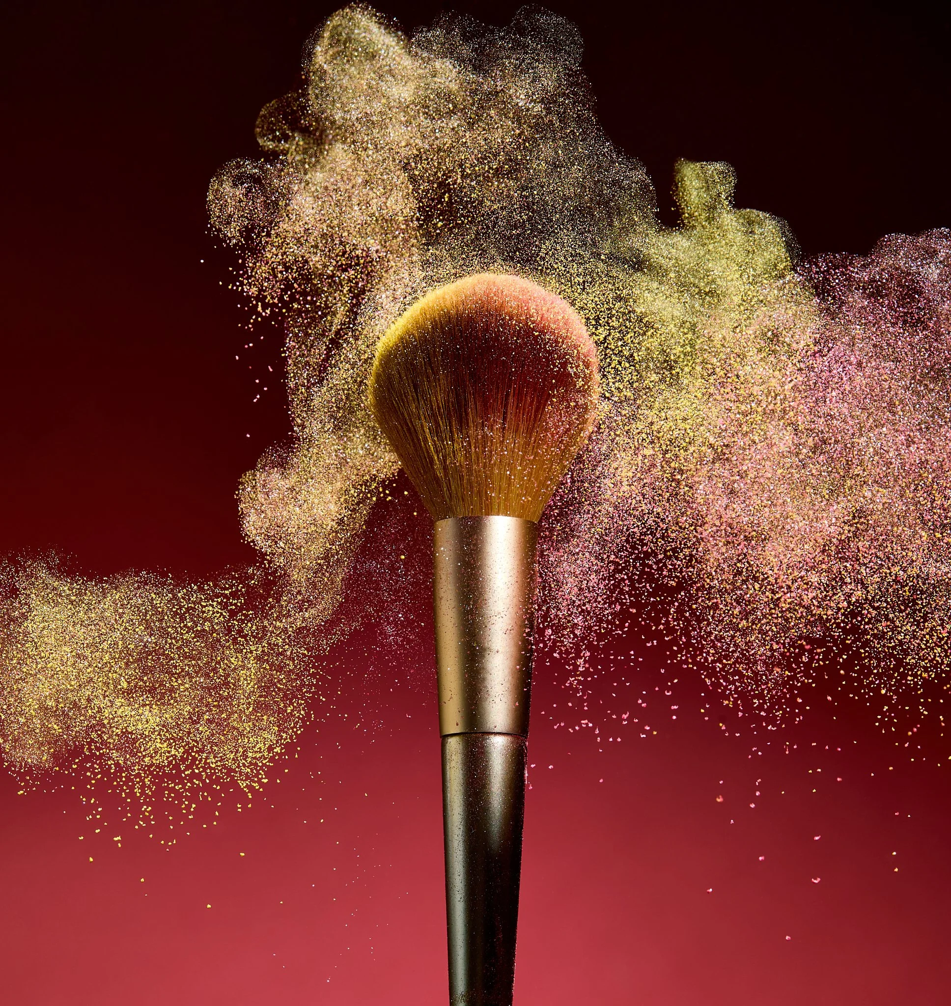 Makeup brush with powder explosion on red background