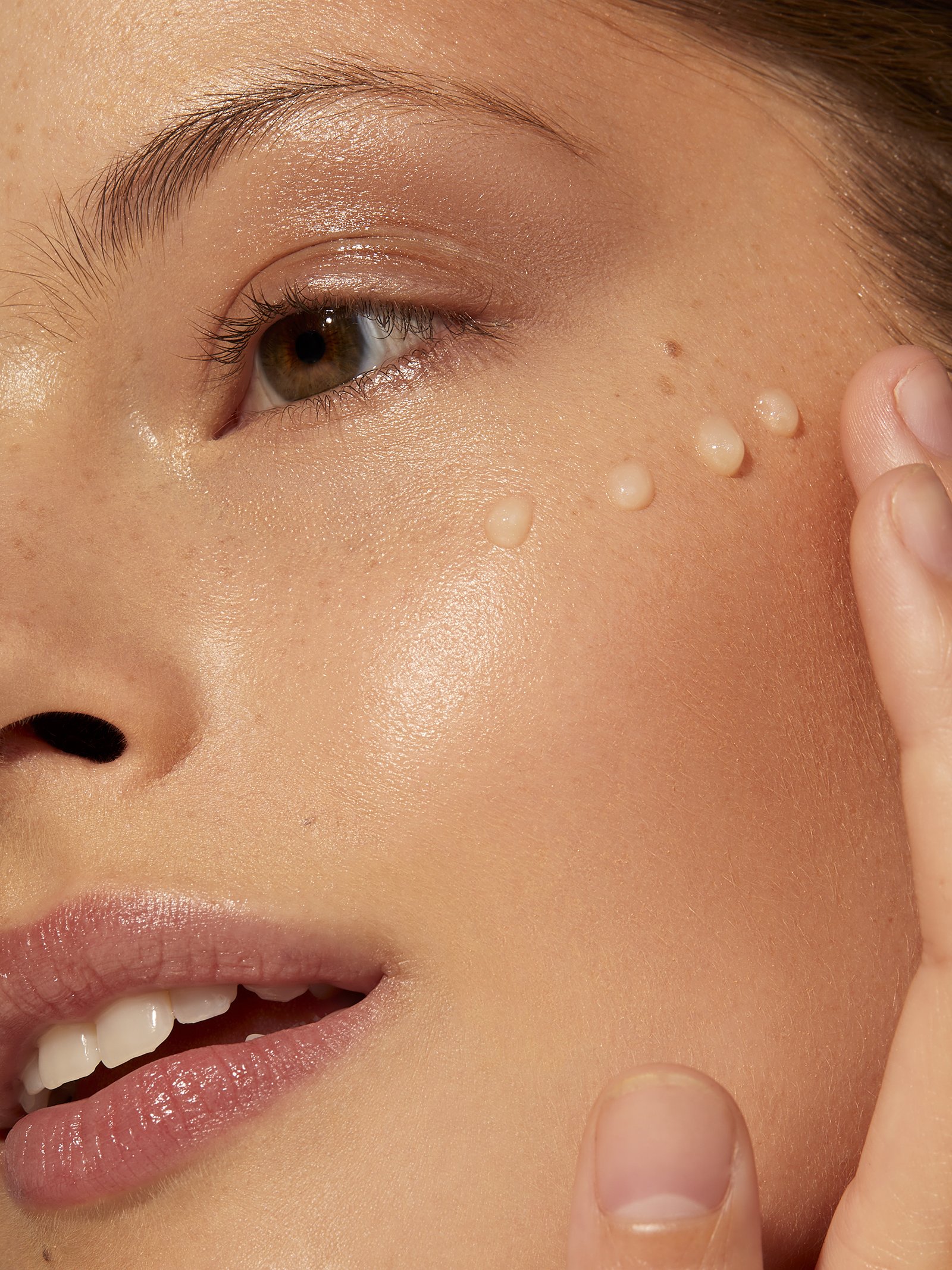 Close-up of a person's face applying skincare product near the eye