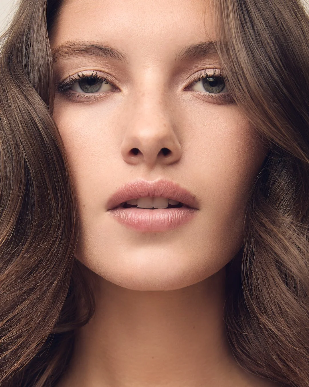 Beauty headshot of a model with natural makeup and clear, even-toned skin looking directly at the camera, captured for a skincare and cosmetics campaign, commercial beauty photography by Adrianna Favero, NYC beauty photographer and director.