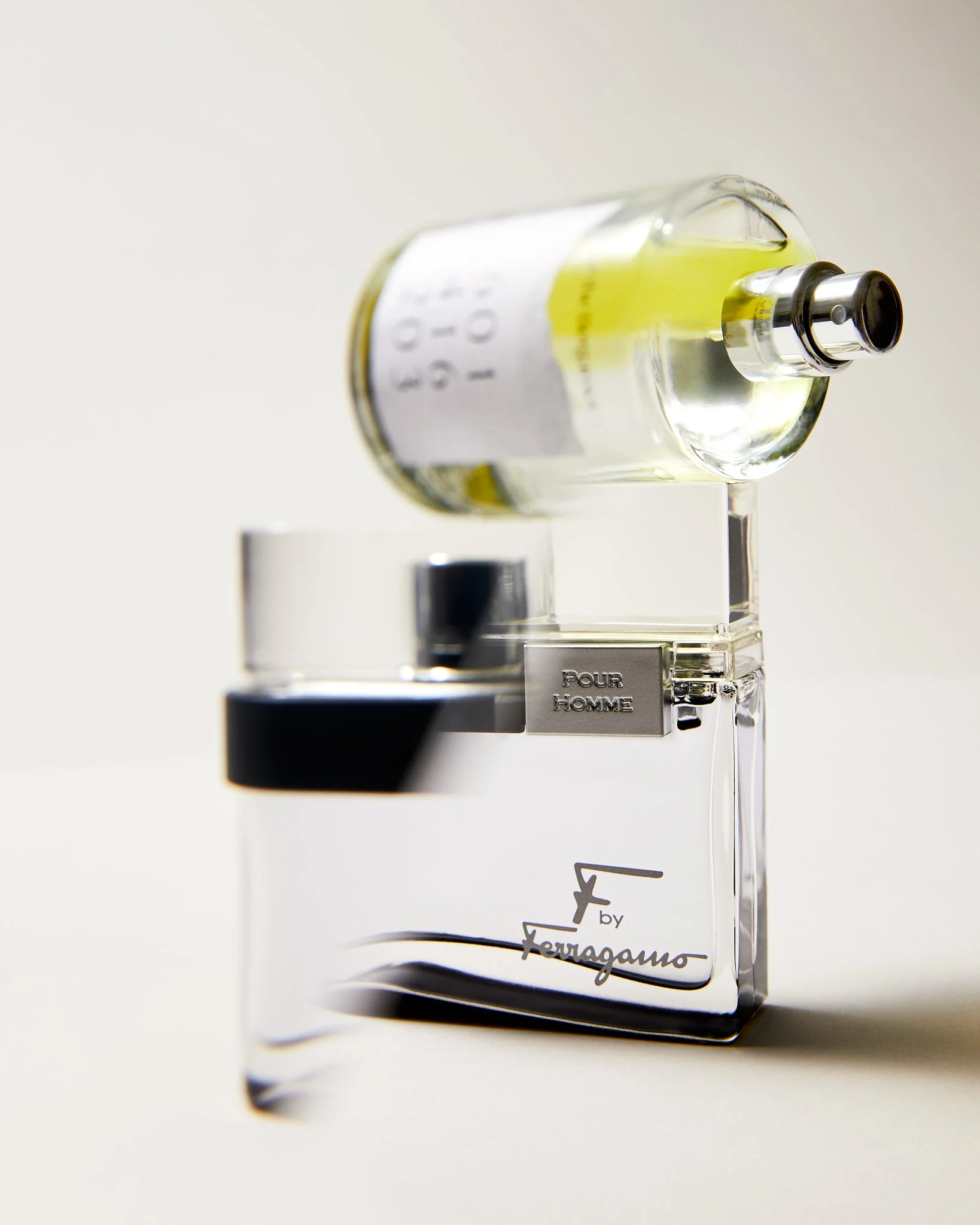 Perfume bottles, including "F by Ferragamo Pour Homme," displayed on a reflective surface.