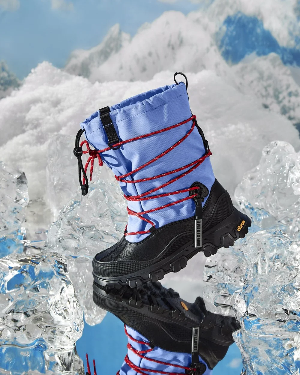 Winter boot with blue upper and red laces on icy background