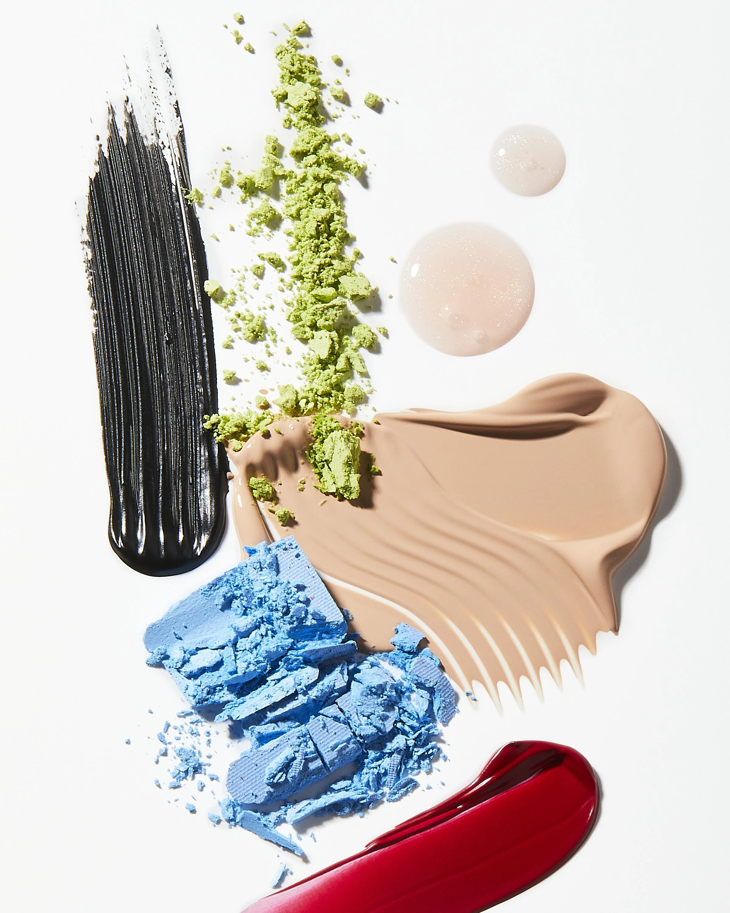 Colorful makeup smears and powders on a white background.