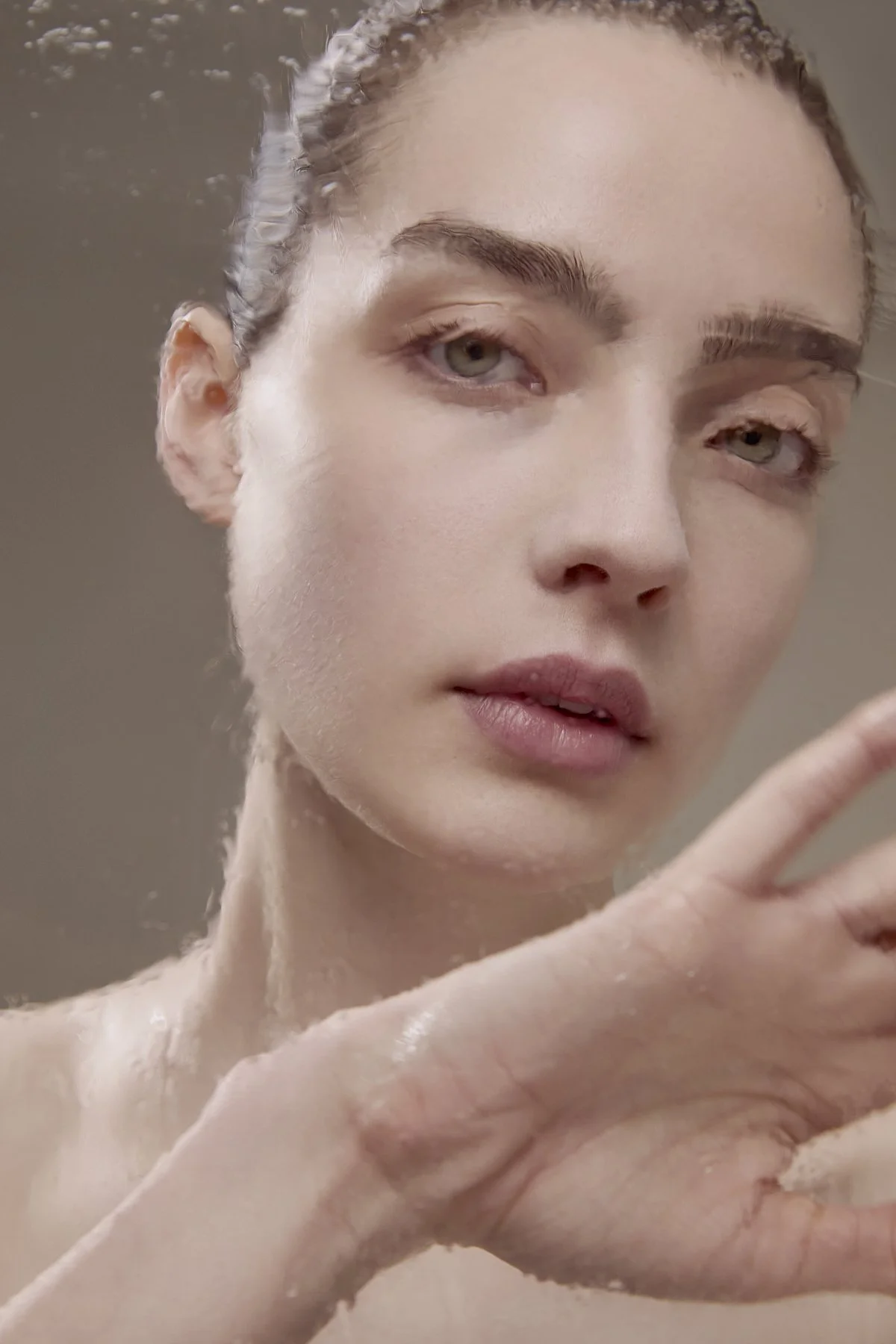 Beauty close-up portrait of a model with natural makeup gently touching her face, showcasing smooth, glowing skin for a skincare and beauty editorial campaign by Adrianna Favero, NYC beauty photographer and director.