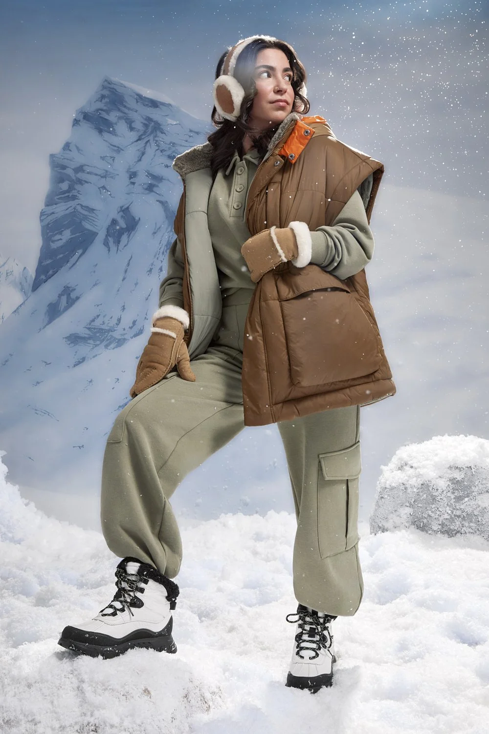 Person in winter attire standing in snowy landscape with mountain in background.