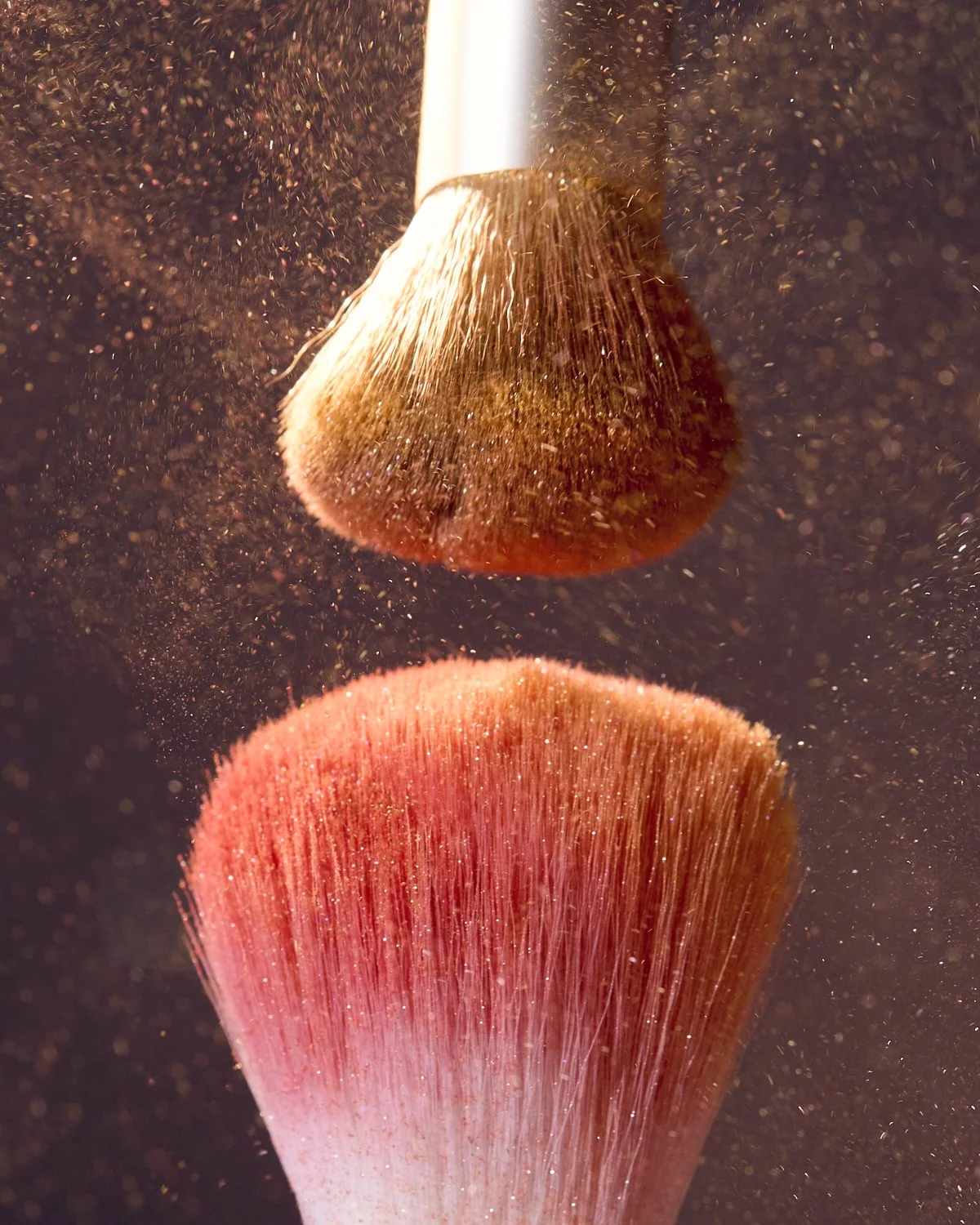 Artistic shot of makeup brushes dusted with warm bronzer pigment powder, by Adrianna Favero.