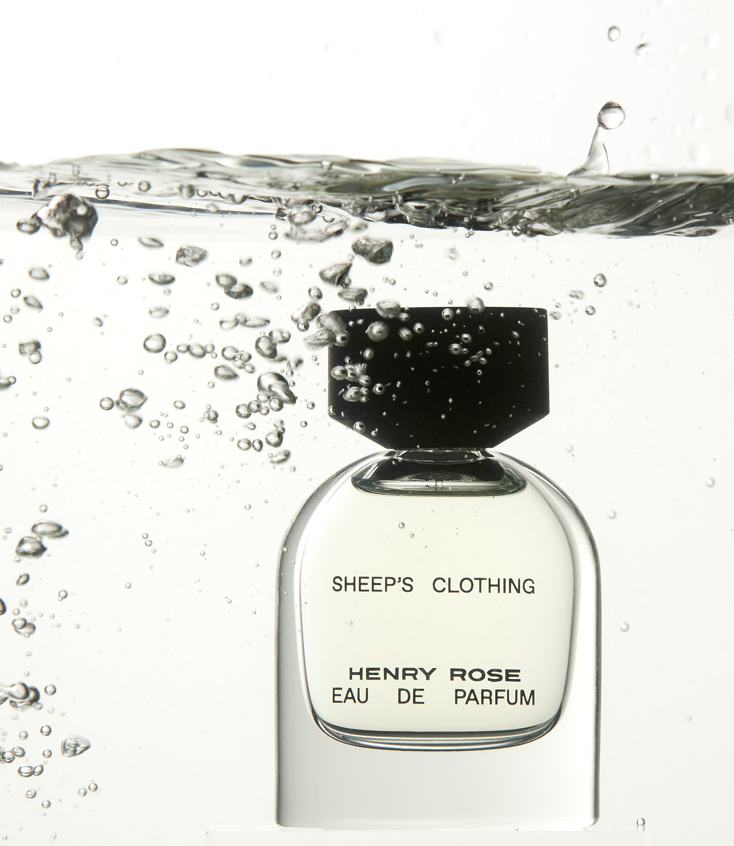 Perfume bottle labeled "Sheep's Clothing" by Henry Rose submerged in water with bubbles.
